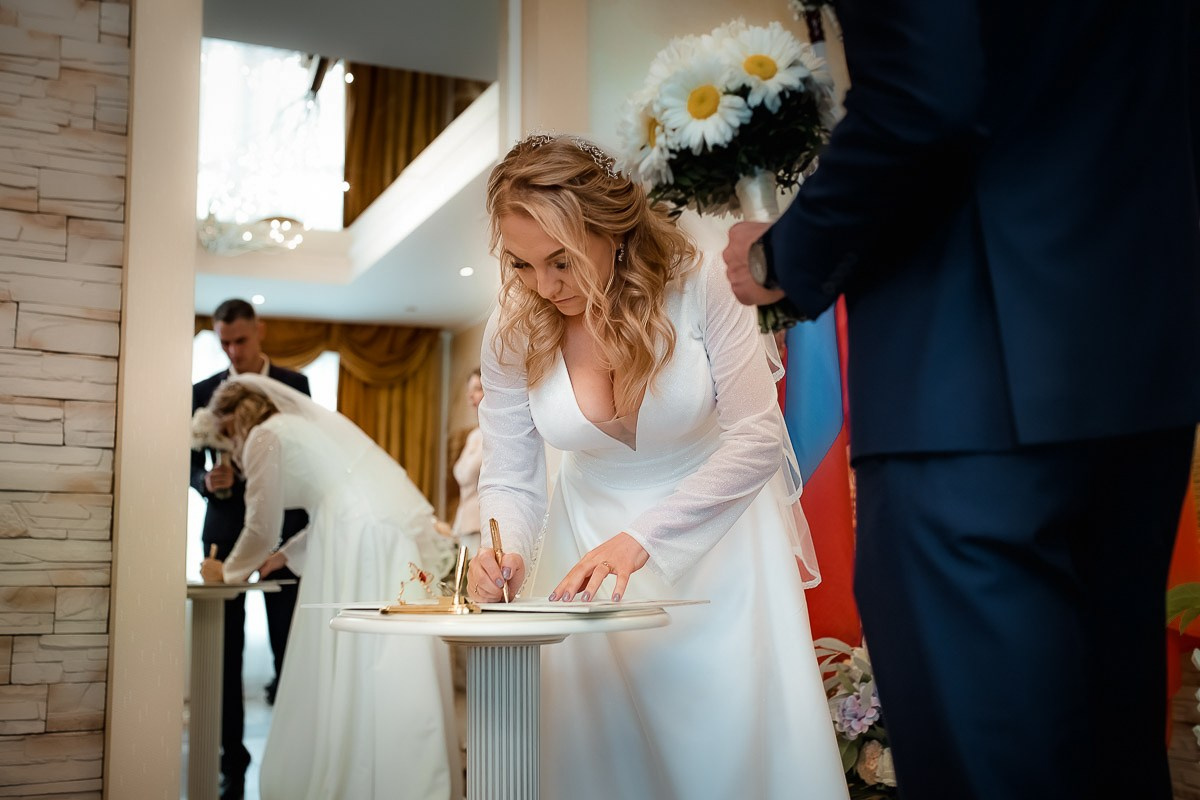 Невеста ставит роспись во время регистрации брака в ЗАГСе на Васильевском острове в Санкт-Петербурге.  Горизонтальный поясной кадр.