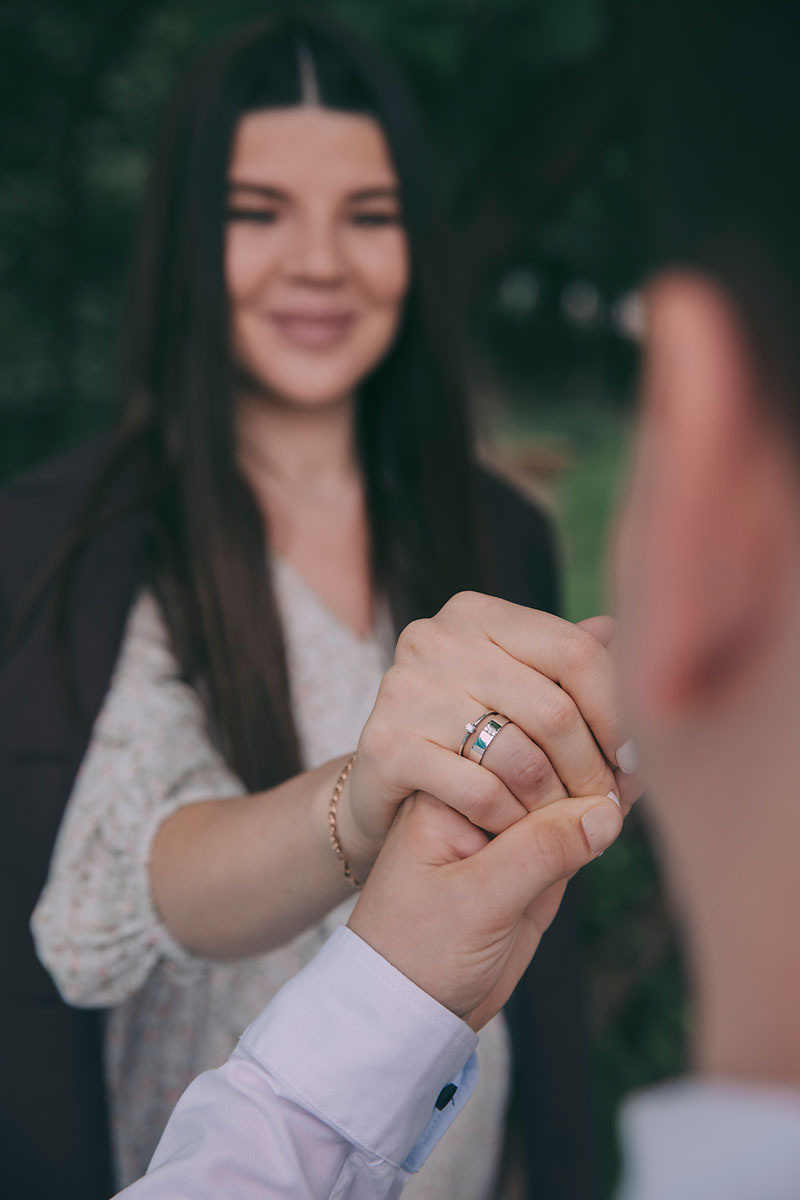 Красивая молодая пара держат друг друга за руку летом  на улице и смотрят друг на друга