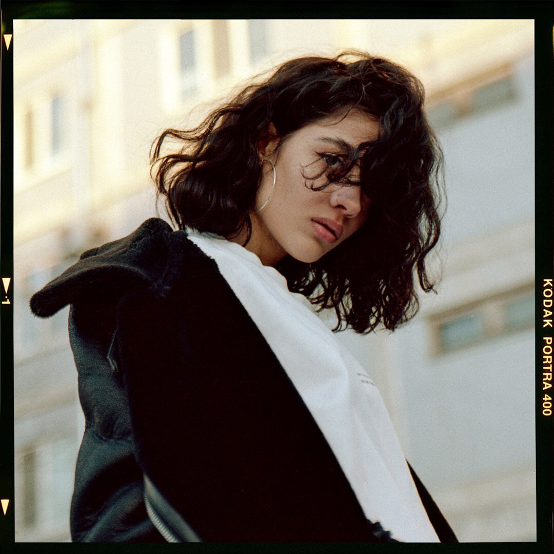 Брюнетка с кучерявий прической наклонила голову 