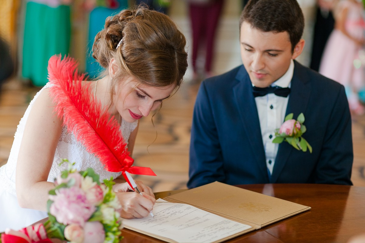 Жених смотрит как невеста расписывается в ЗАГСе