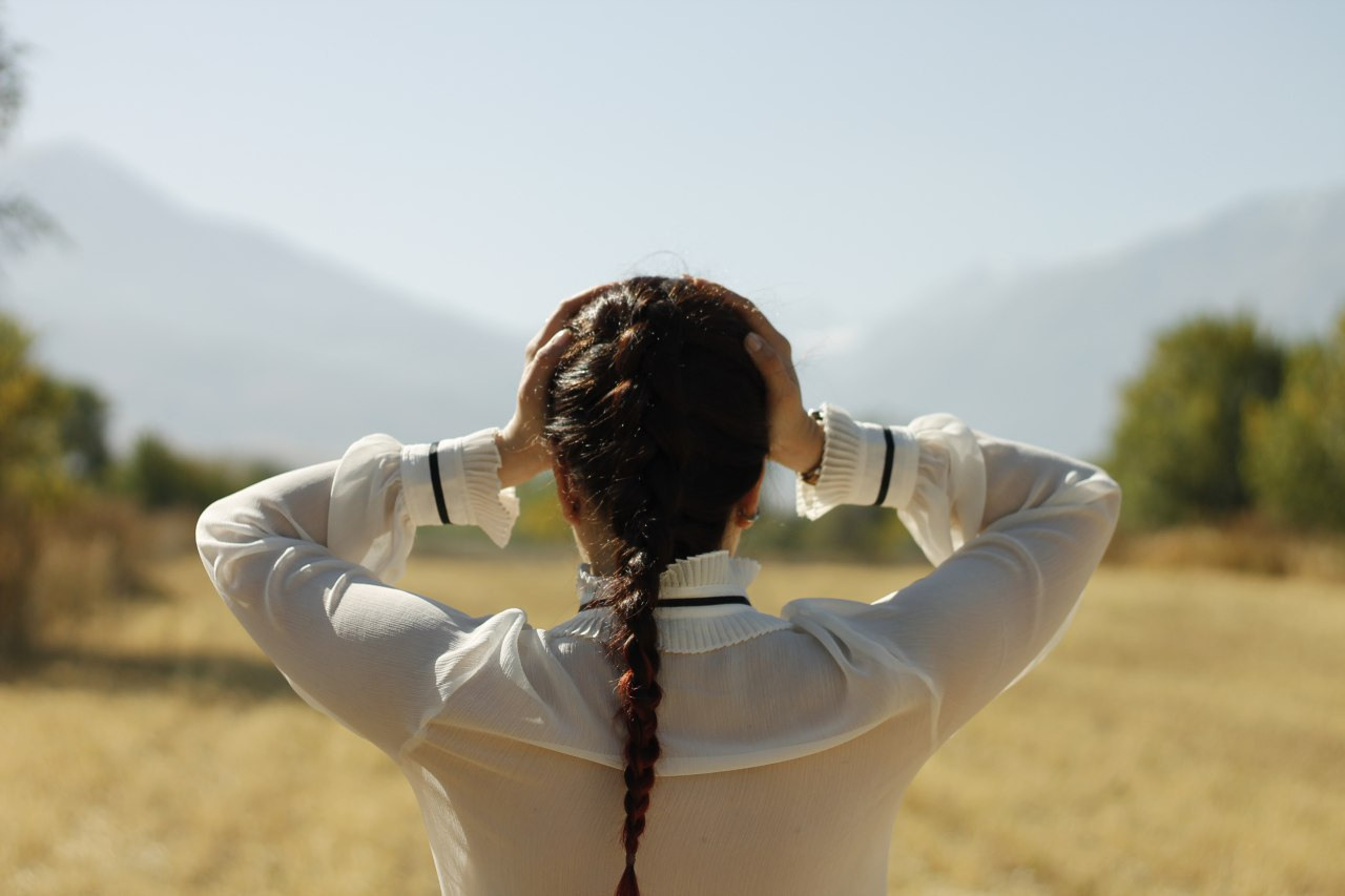 Woman catching her head with two hands with mountains on the background