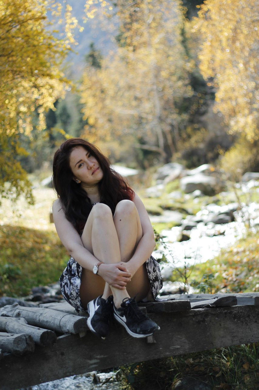 Woman sitting on a little bridge in autumn mountains 