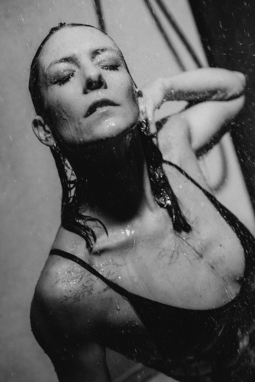 Эффектная женская фотосессия — модель в черном купальнике под душем, свет и вода, художественная фотосъемка