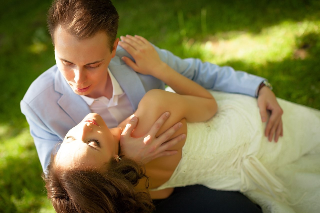 молодожены на зеленой траве в парке. жених нежно держит невесту на руках