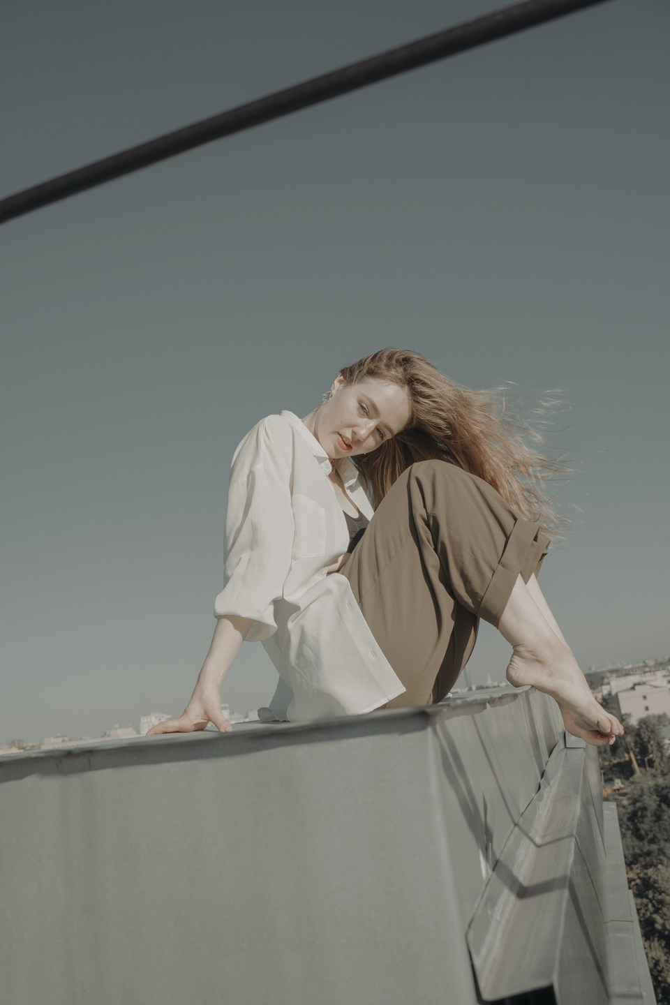 Фотография девушки сидящей на крыше смотрящий в камеру