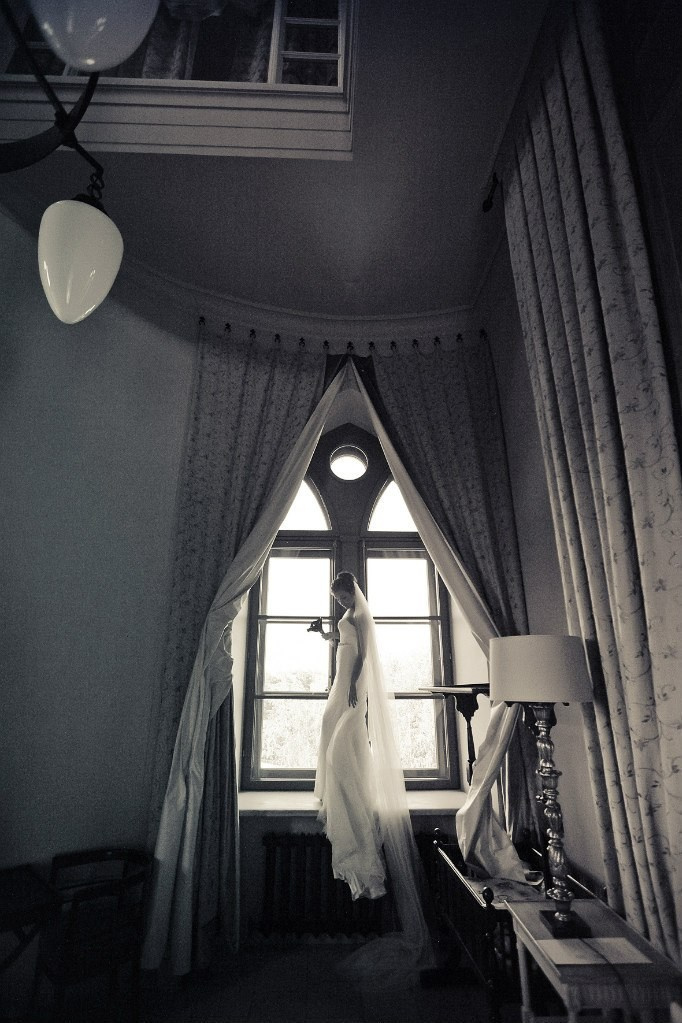 невеста на черно белой фотографии на фоне окна и светлых штор в гостинечном номере