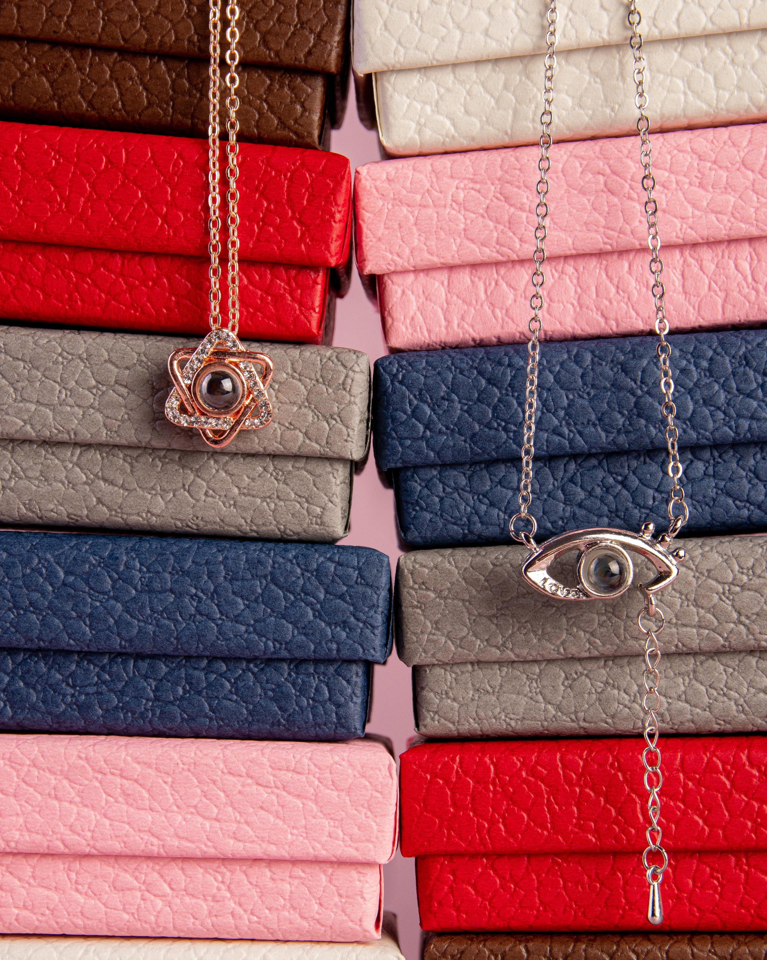 Предметная съемка ювелирных украшений — кулоны на цепочке с глазом на фоне цветных коробочек, фотография для каталога и маркетплейса