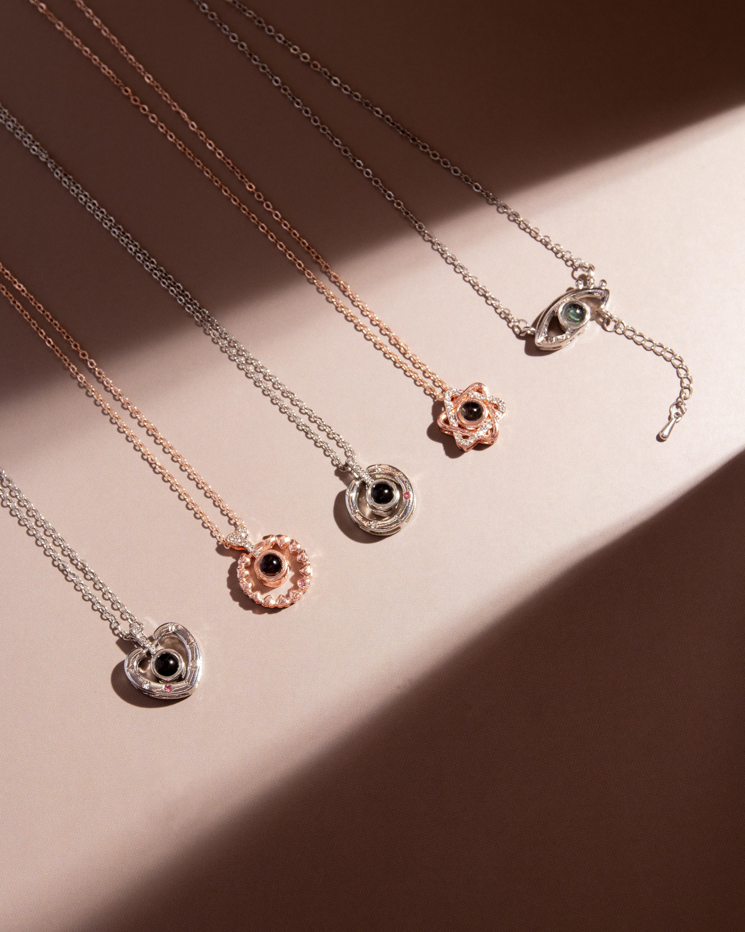 Предметная фотография в Новороссийске, Анапе, Краснодаре, Геленджике, кулонов на цепочках с декоративным глазом на бежевом фоне с мягким светом