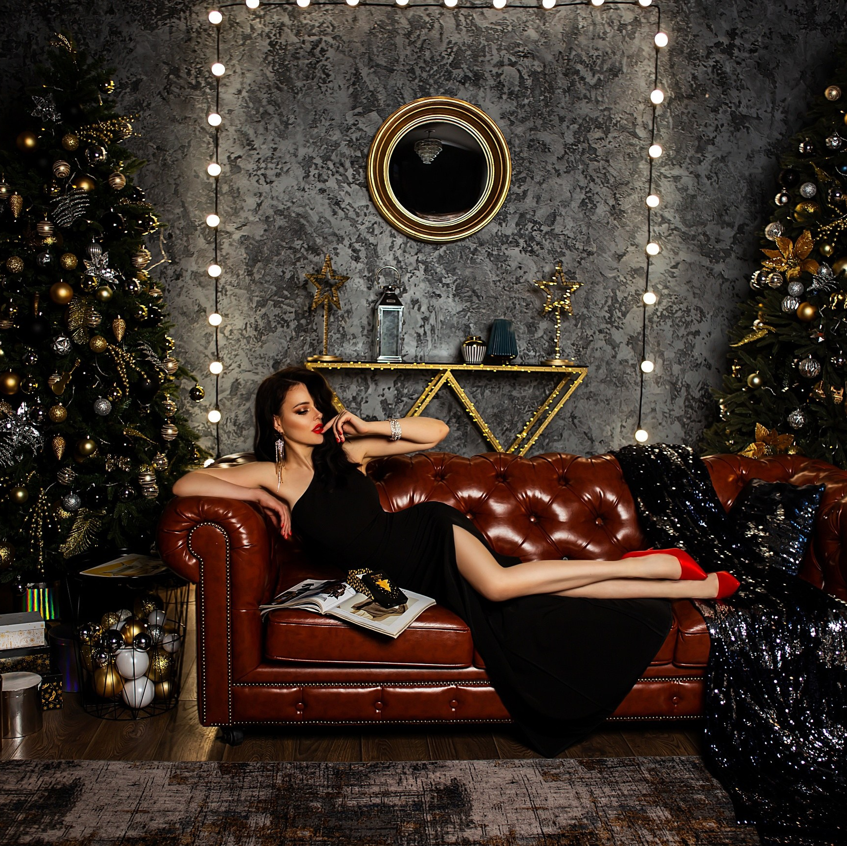 Девушка в черном платье лежит на кожаном диване