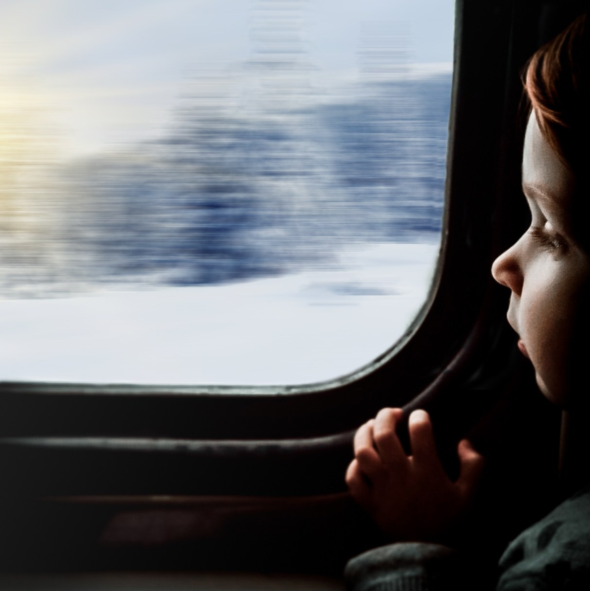 Ребёнок смотрит в окно движущегося поезда на размытый заснеженный пейзаж. Стрит-фотография Мальцева Евгения.