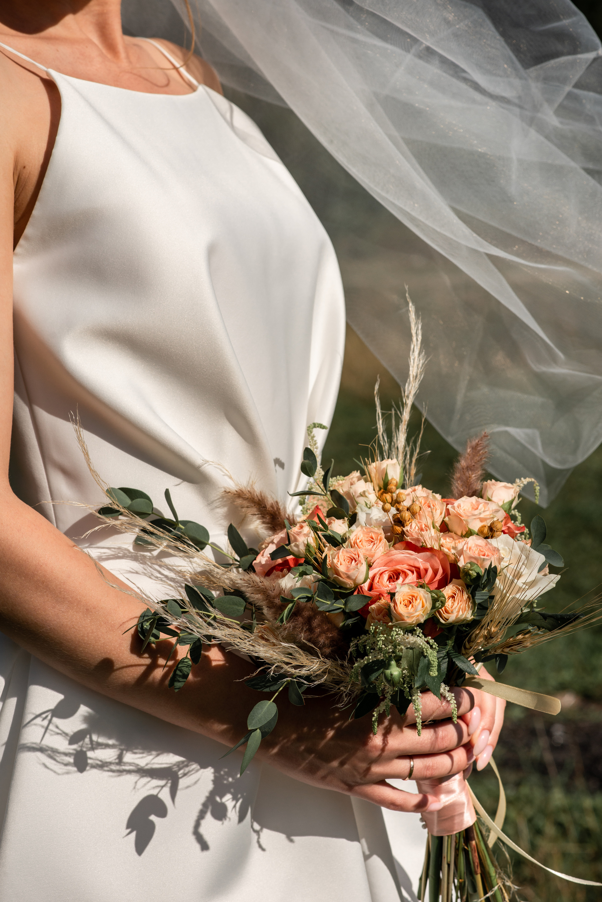 невеста держит букет развивается фата на ветру