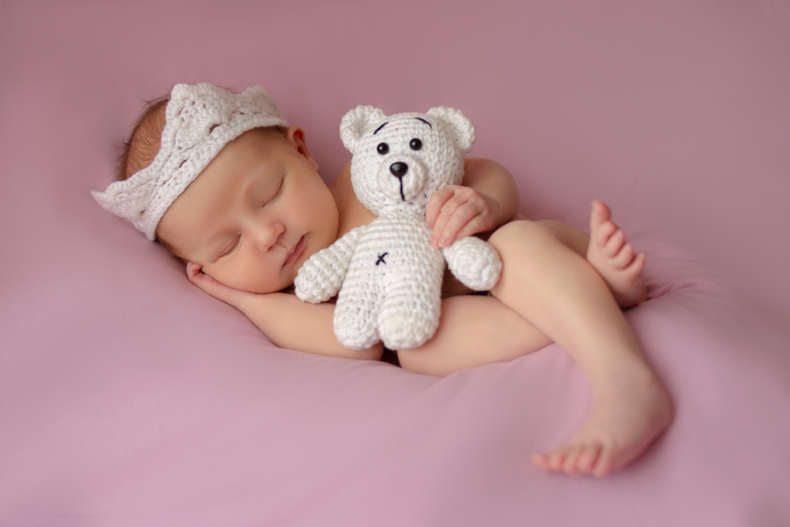 спящий ребенок на розовом фоне с медвежонком в руках