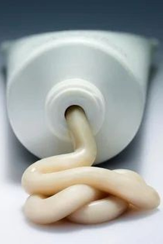 Предметная съемка зубной пасты на зеркальной поверхности с мягким светом.