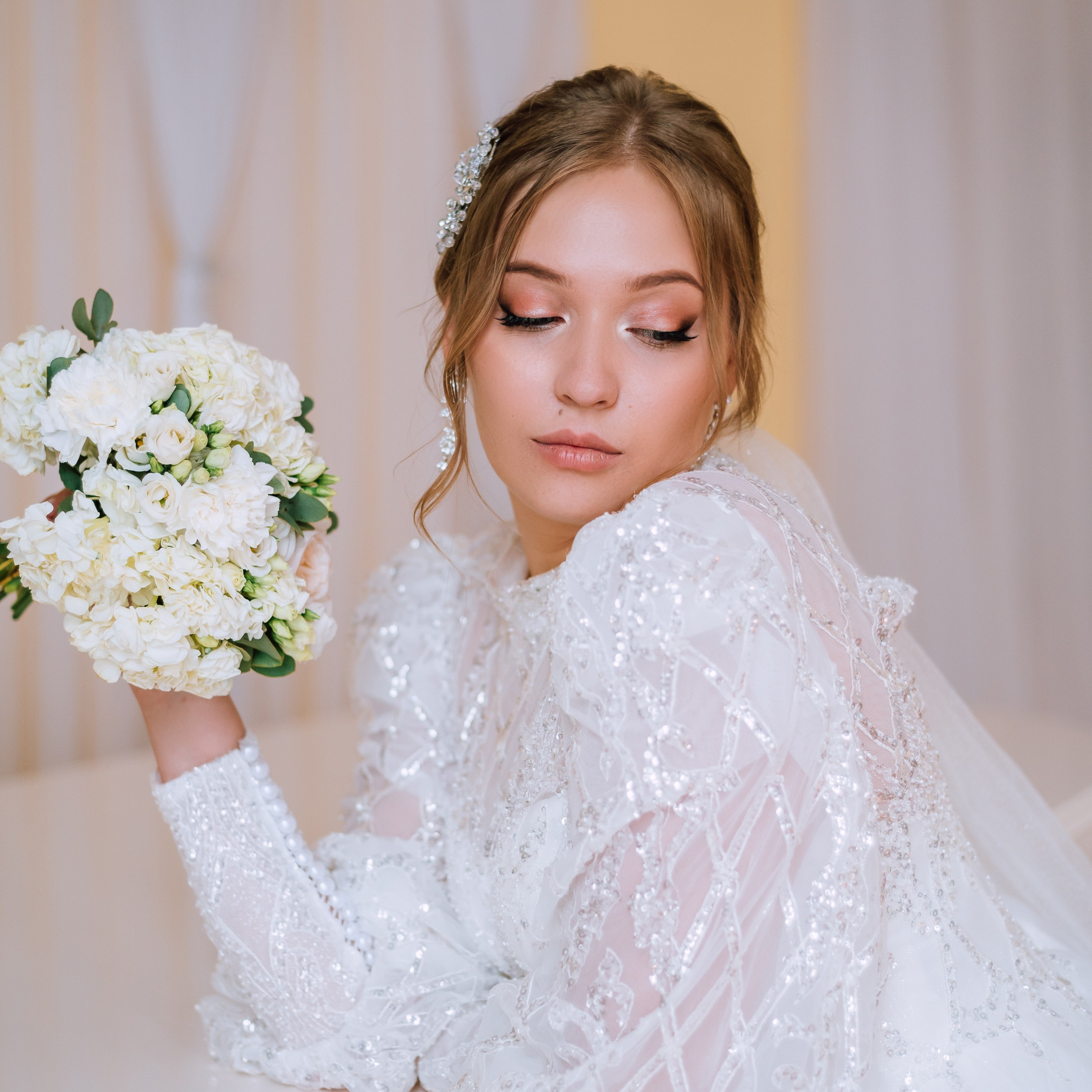 Невеста с белым букетом в руках смотрит вниз, облокотившись на рояль