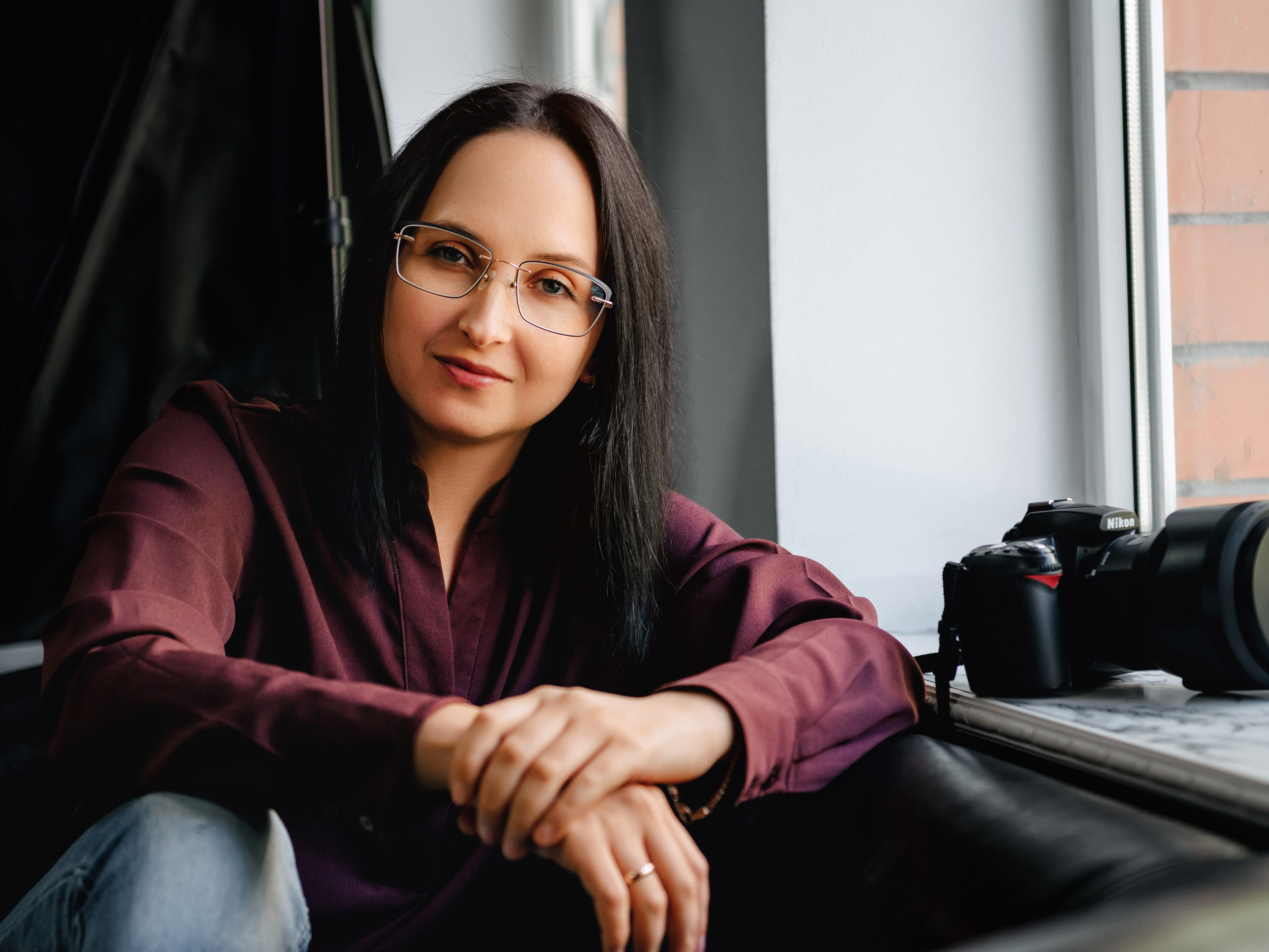 Девушка фотограф Мария Прищеп держит в руках фотоаппарат и приветливо улыбается