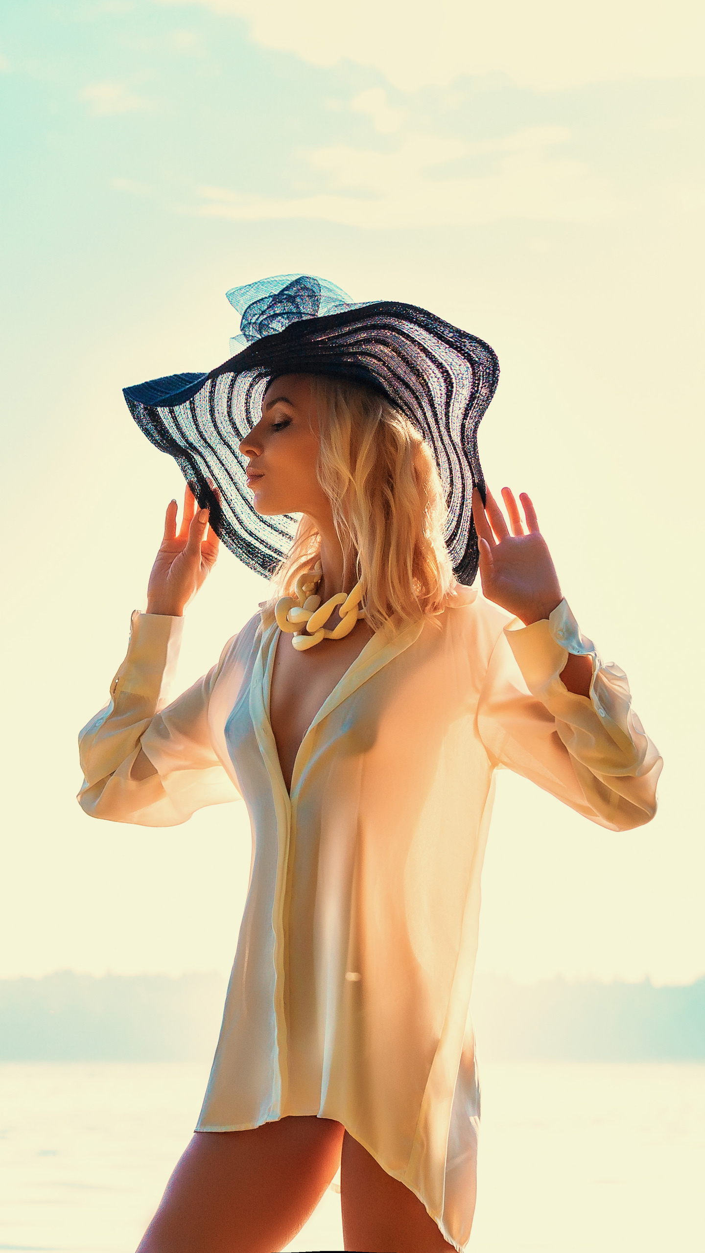 девушка в белой рубашке и черной шляпе на озере