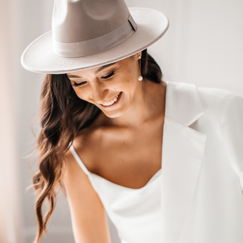 Портрет стильной красивой девушки в белом пиджаке и шляпе.