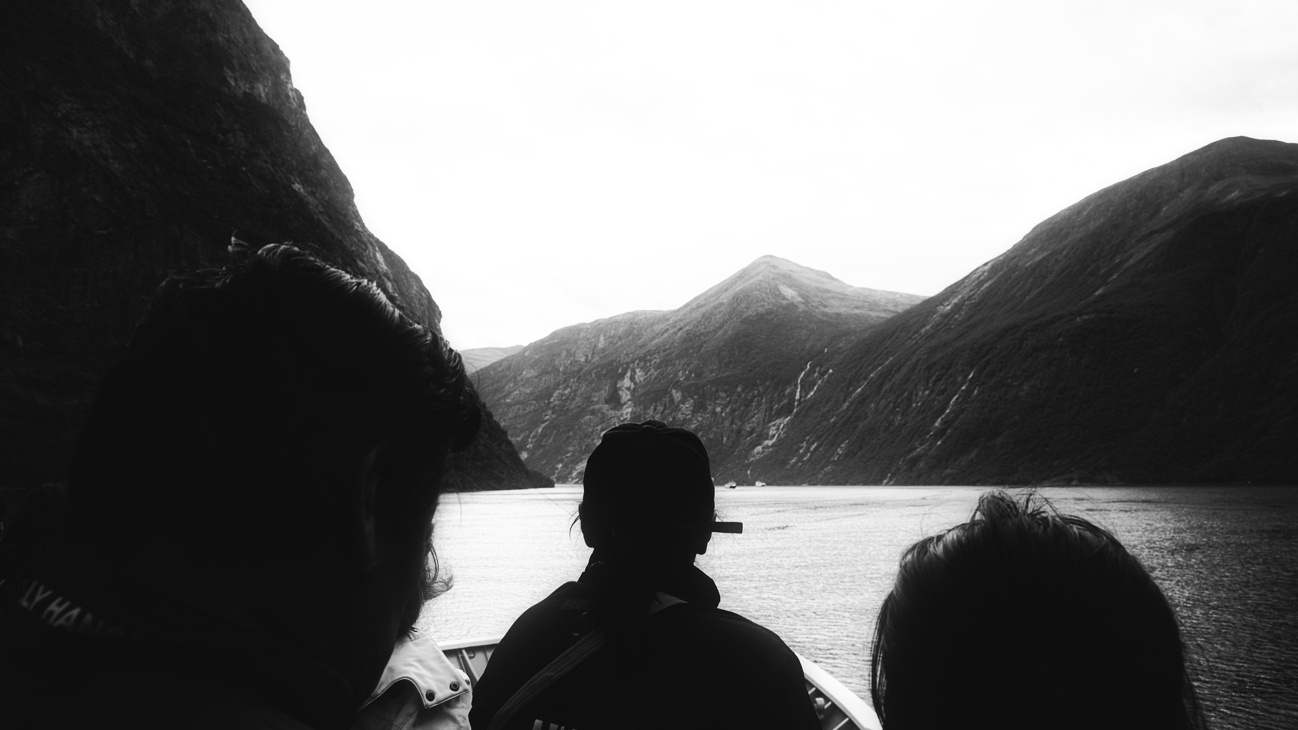 Черно-белая фотография: силуэты людей на лодке смотрят на фьорд и горы, Норвегия, путешествие, созерцание природы, пейзаж