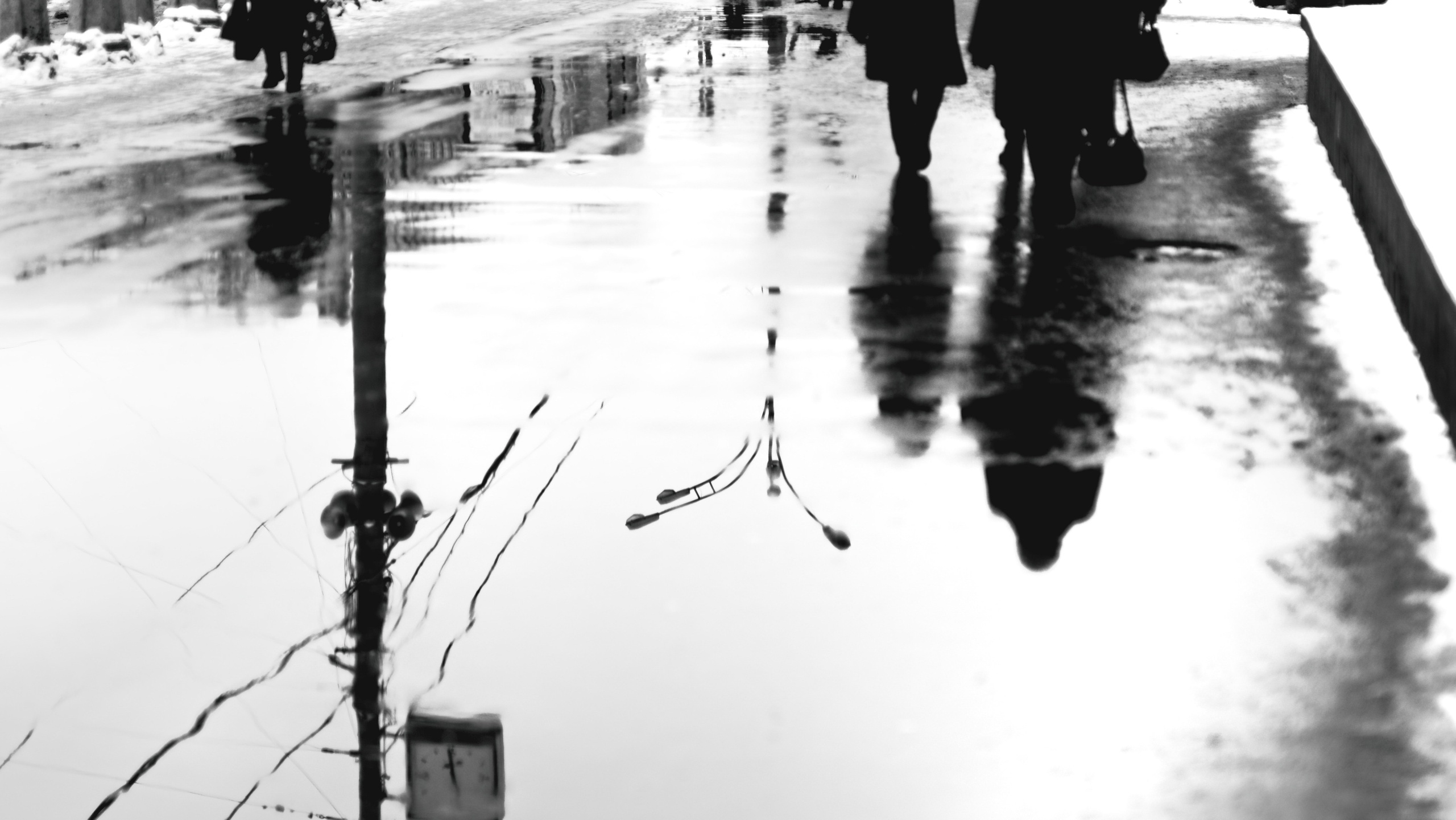 Художественное отражение в луже силуэтов людей и проводов, черно-белая абстракция, размытая геометрия