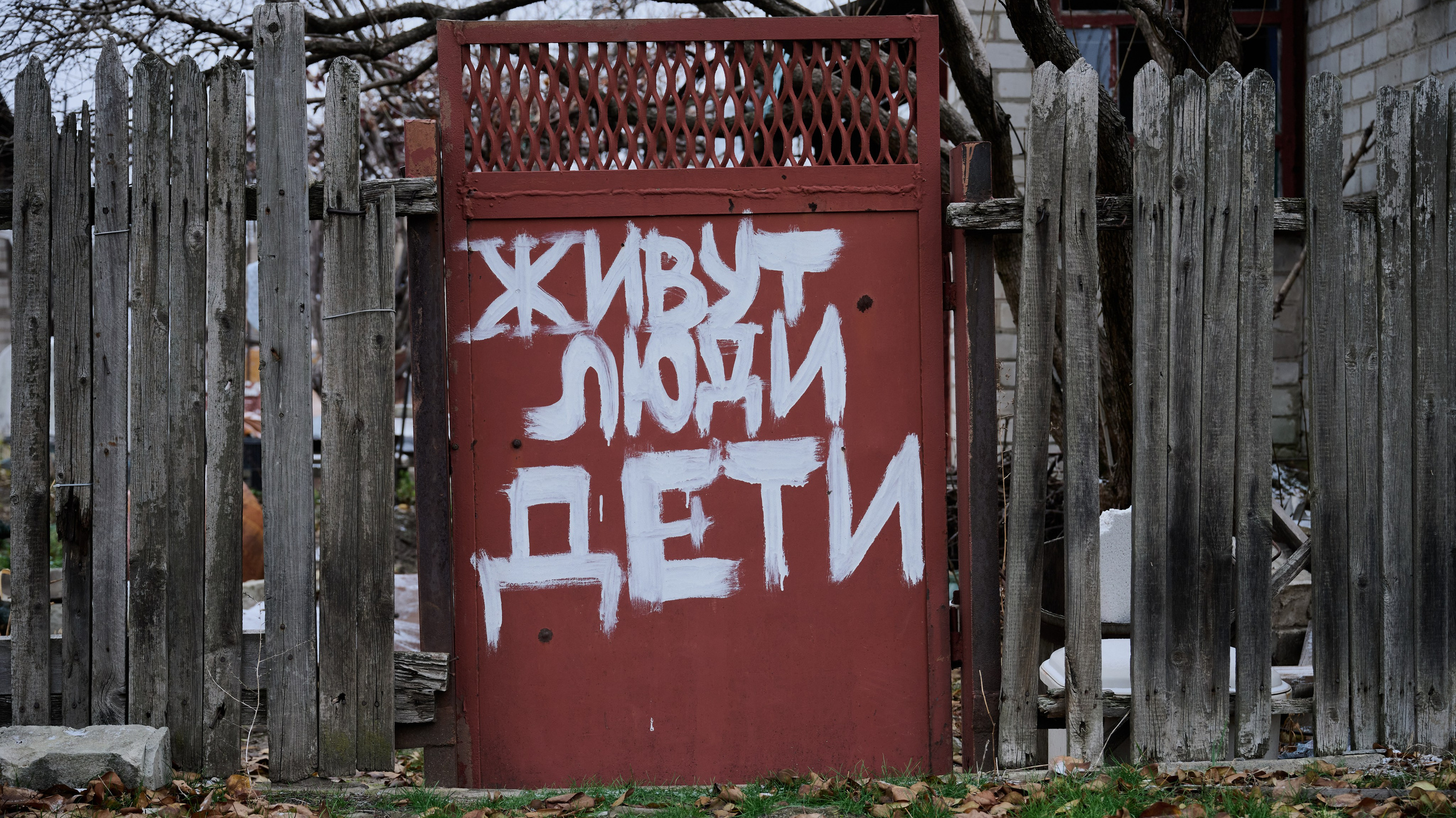 Старая деревянная калитка с надписью белой краской «Живут люди дети». Документальная фотография проекта The Humans v.21. Манифест человечности.