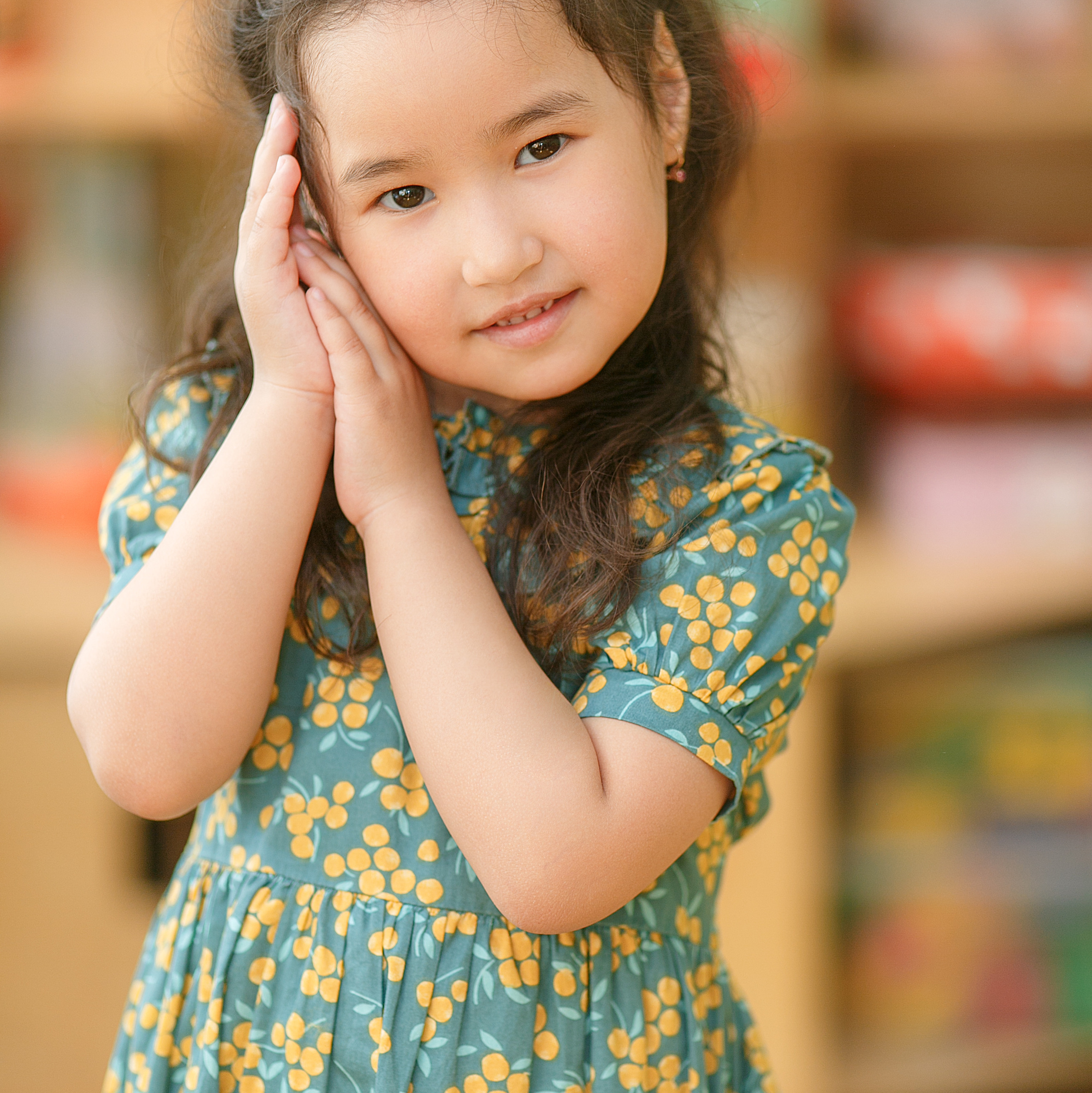 Ученица в белой рубашке с красивыми лококами облокотилась на парту.