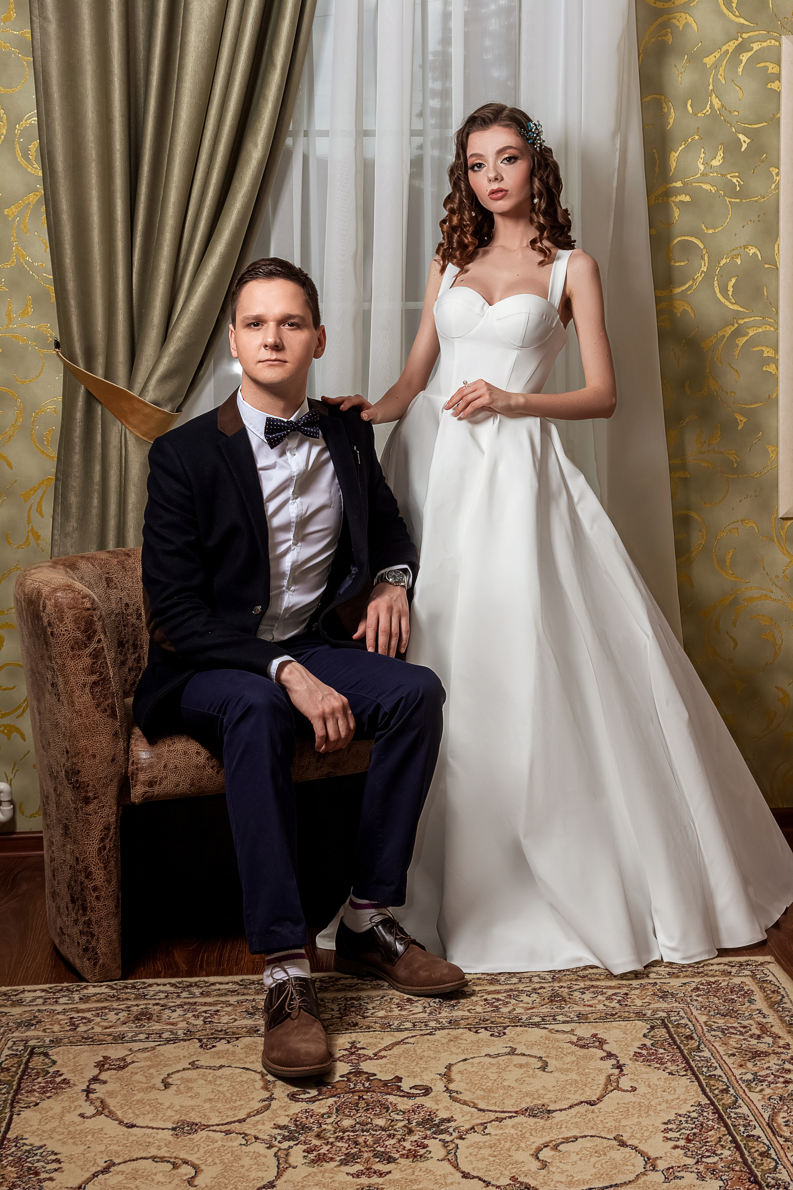 Молодожены в роскошном номере частного отеля "Барин", жених в кожаном кресле на фоне оливковых портьер.