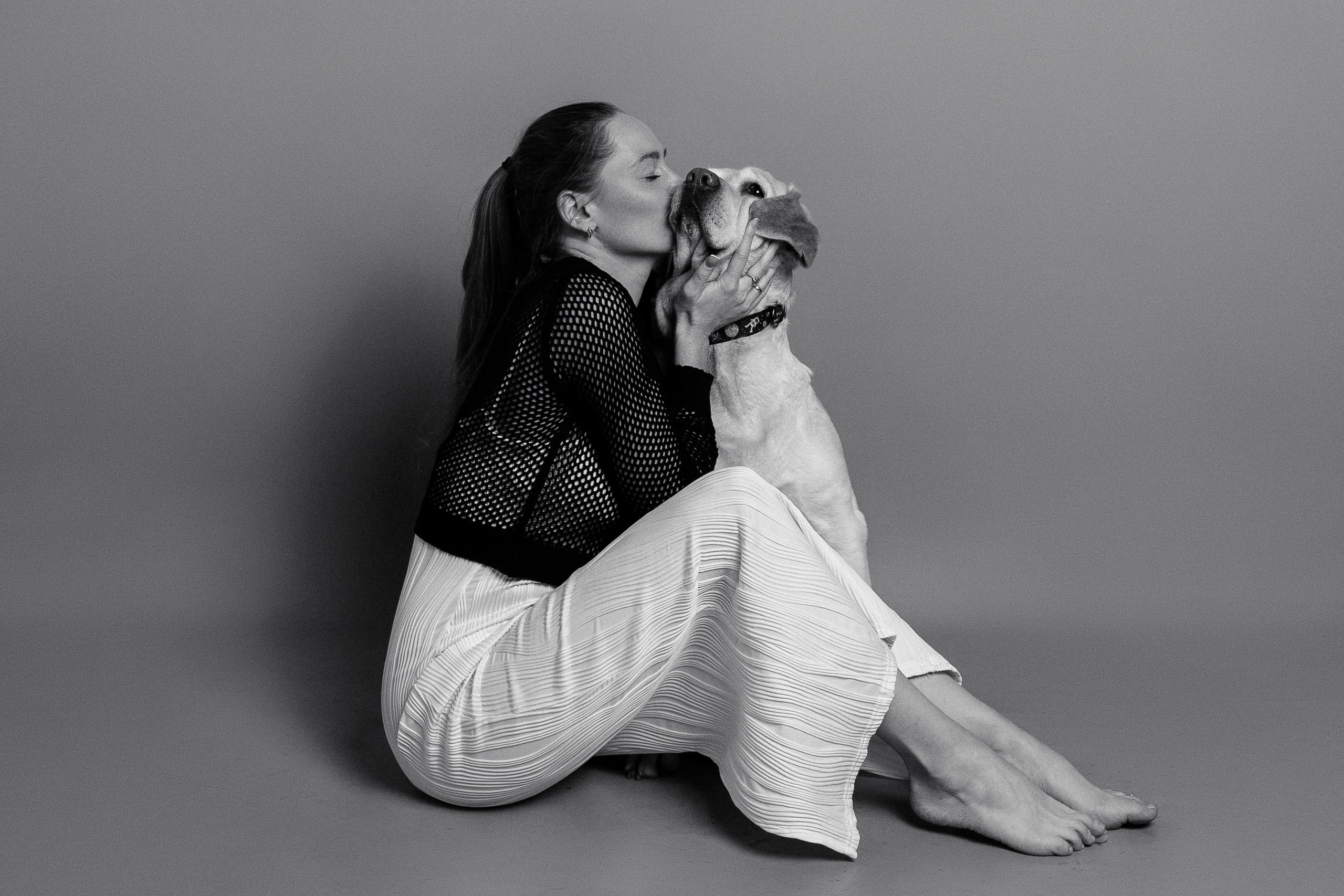 Девушка сидит на полу в фотостудии вместе со своей любимой собакой черно белая фотография