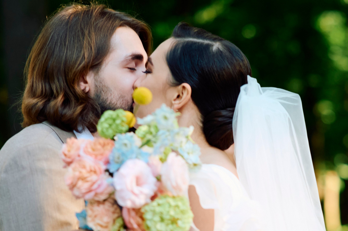 Свадебный фотограф в Москве и Петербурге — невеста и жених обнимаются и скрывают свои эмоции букетом, потому что их снимает лучший фотограф