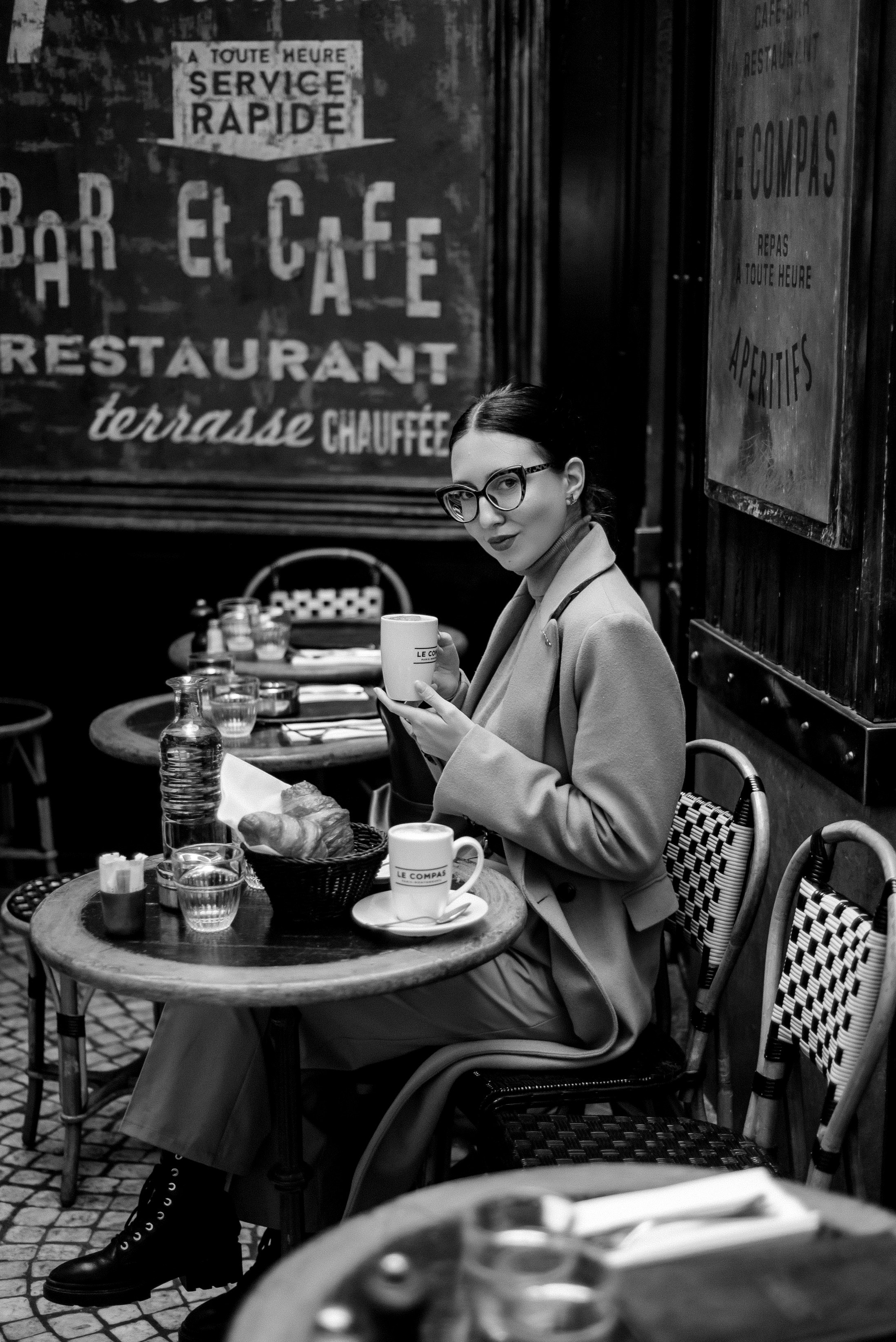 Девушка в очках сидит в кафе в Париже