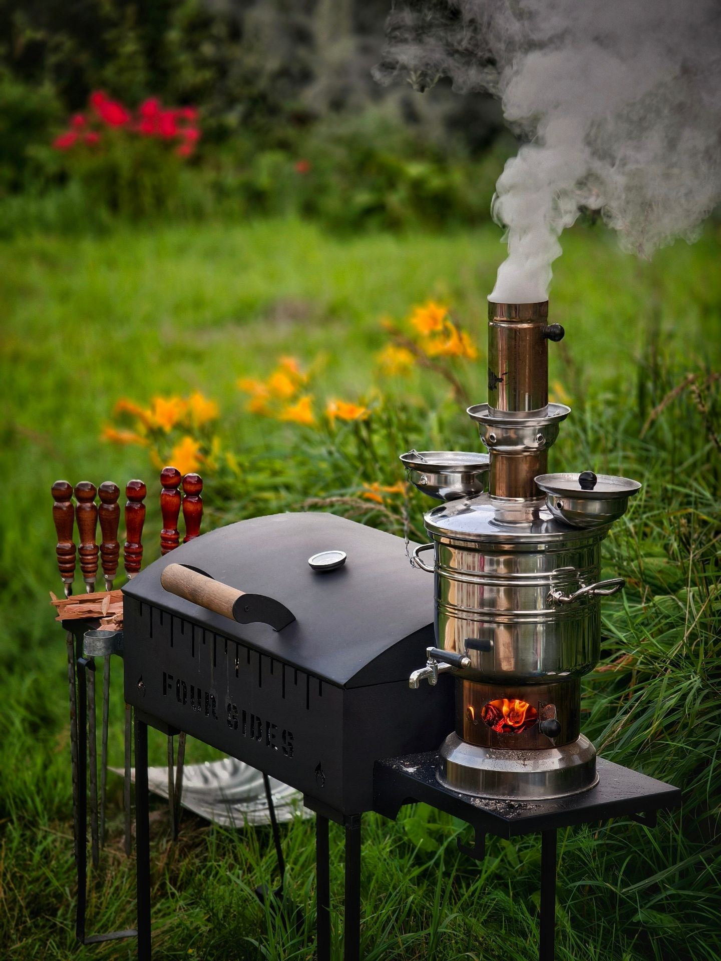 Самовар на дровах и мангал с шашлыками на фоне зеленой лужайки