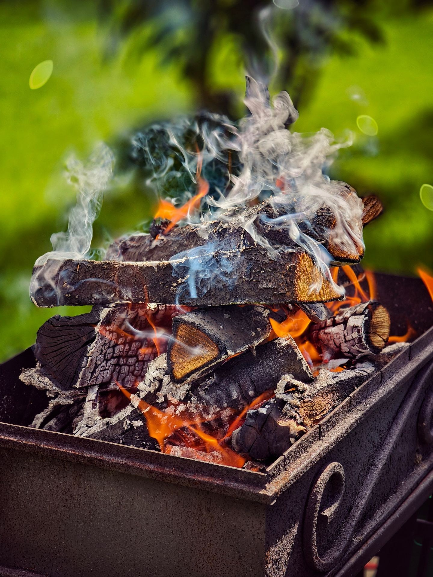 Дрова горят в мангале на зеленом фоне