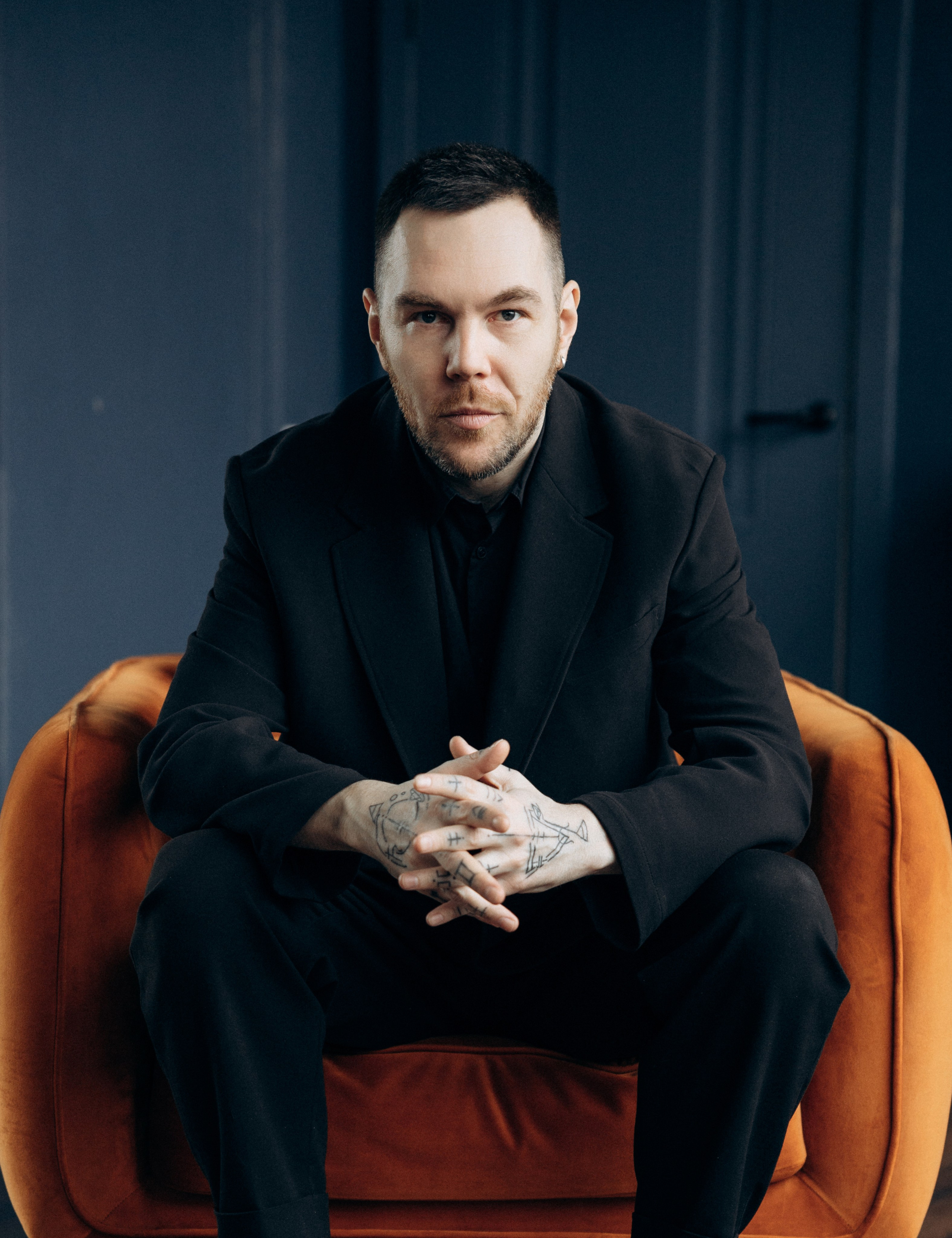 Портрет фотографа Дениса Медоваров сидящего летом в солнгечных очках ан асфальте