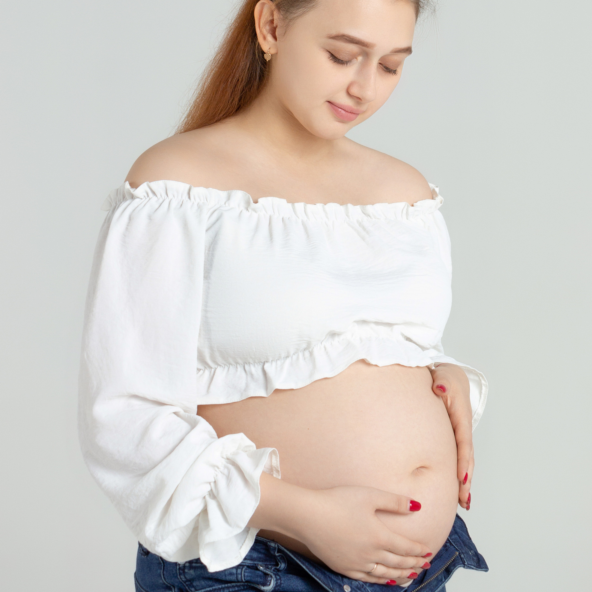 беременная девушка в джинсах и белом топе