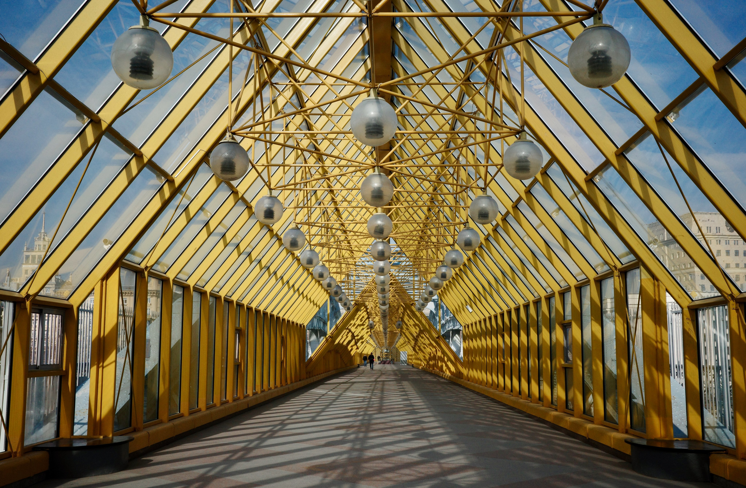 Перспектива Андреевского пешеходного моста: золотистый каркас уходит вдаль, шаровидные фонари