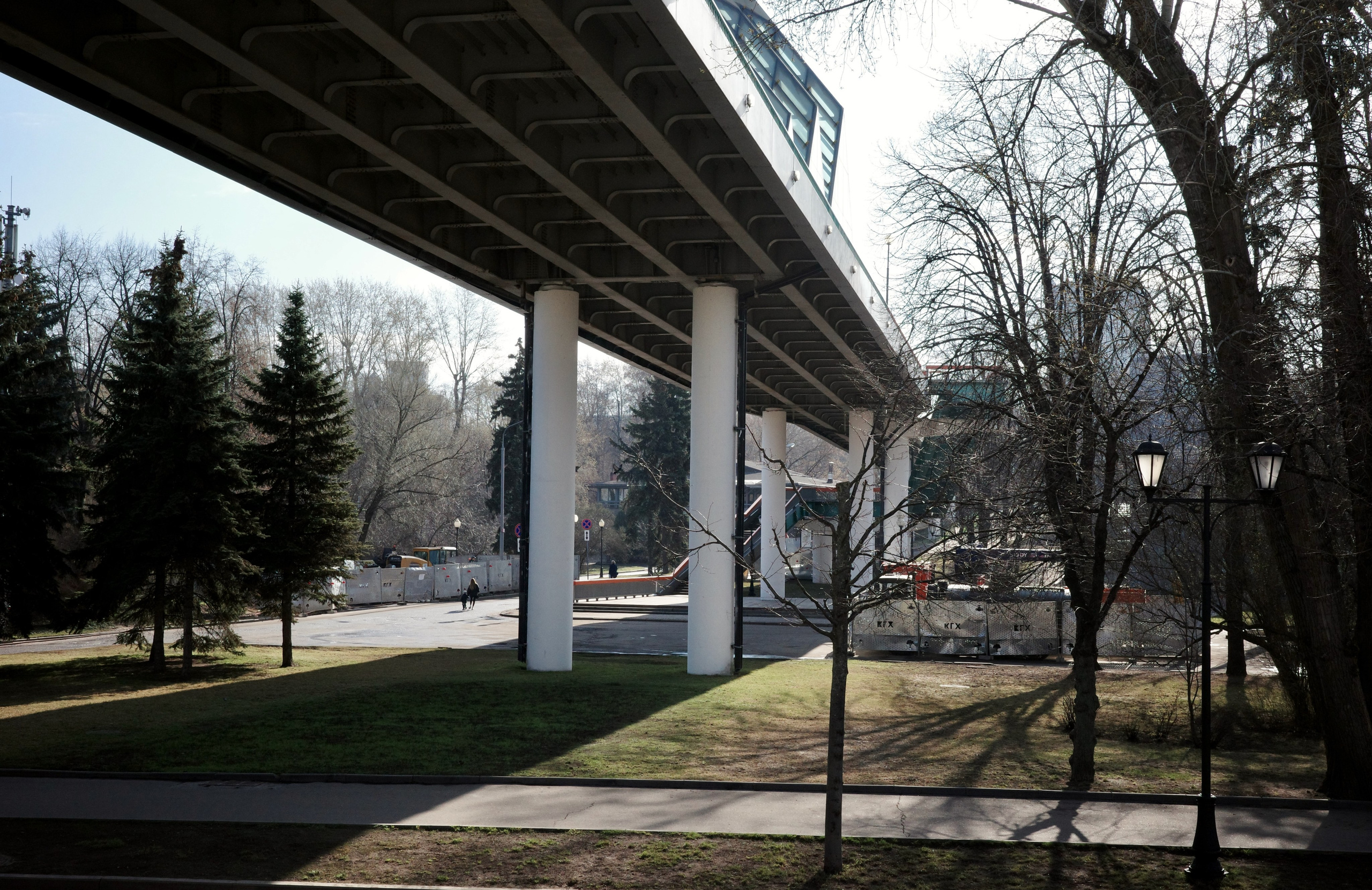 Под Андреевским мостом: бетонные опоры, зелёная лужайка, ели и старинный фонарь в Нескучном саду