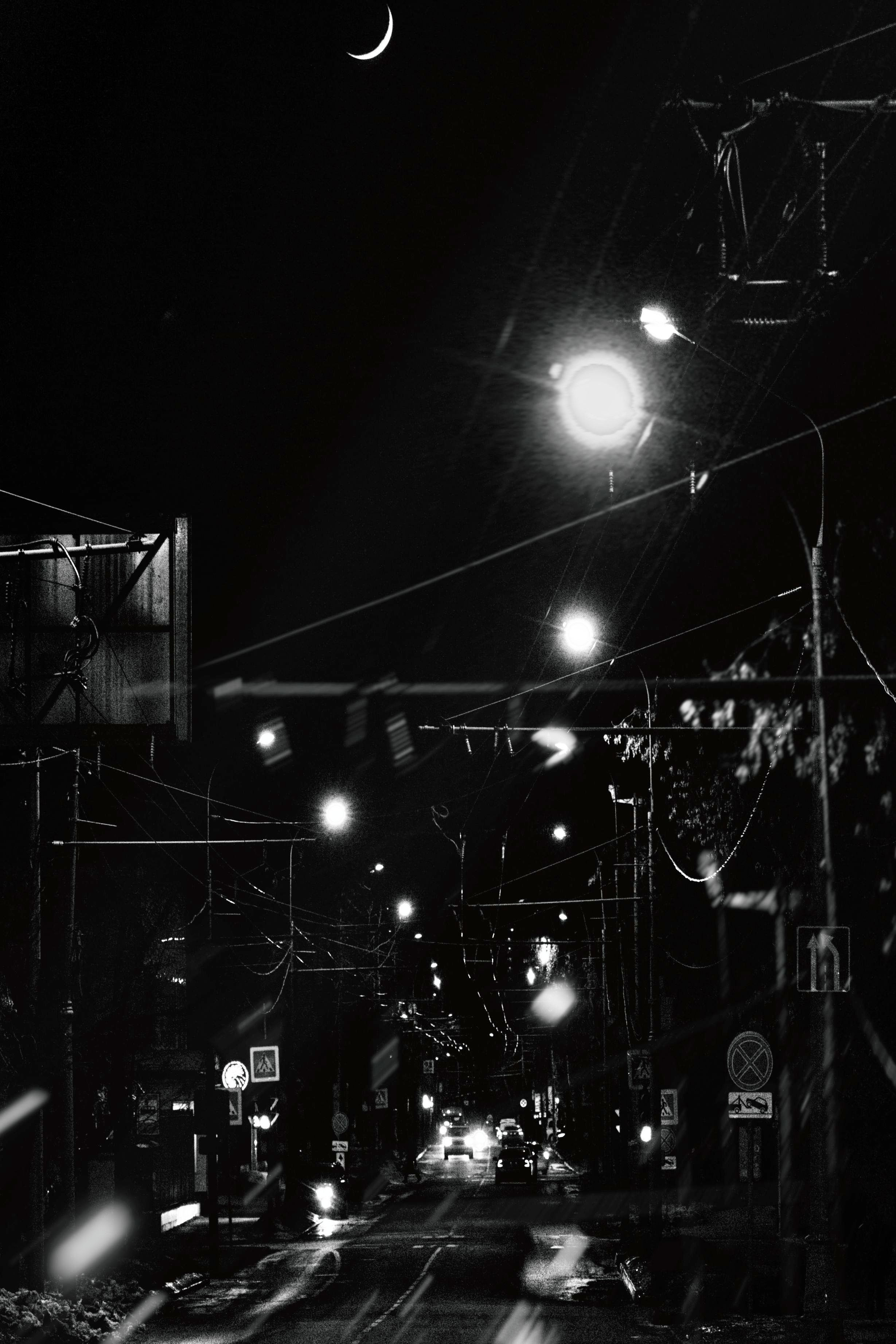 Ночная городская улица с луной, уличными фонарями и переплетающимися проводами, черно-белое фото с эффектом боке