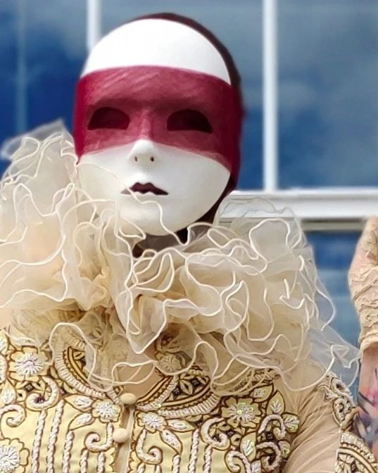 Мим в маске и в красной повязке на раусе у окна встречает гостей.