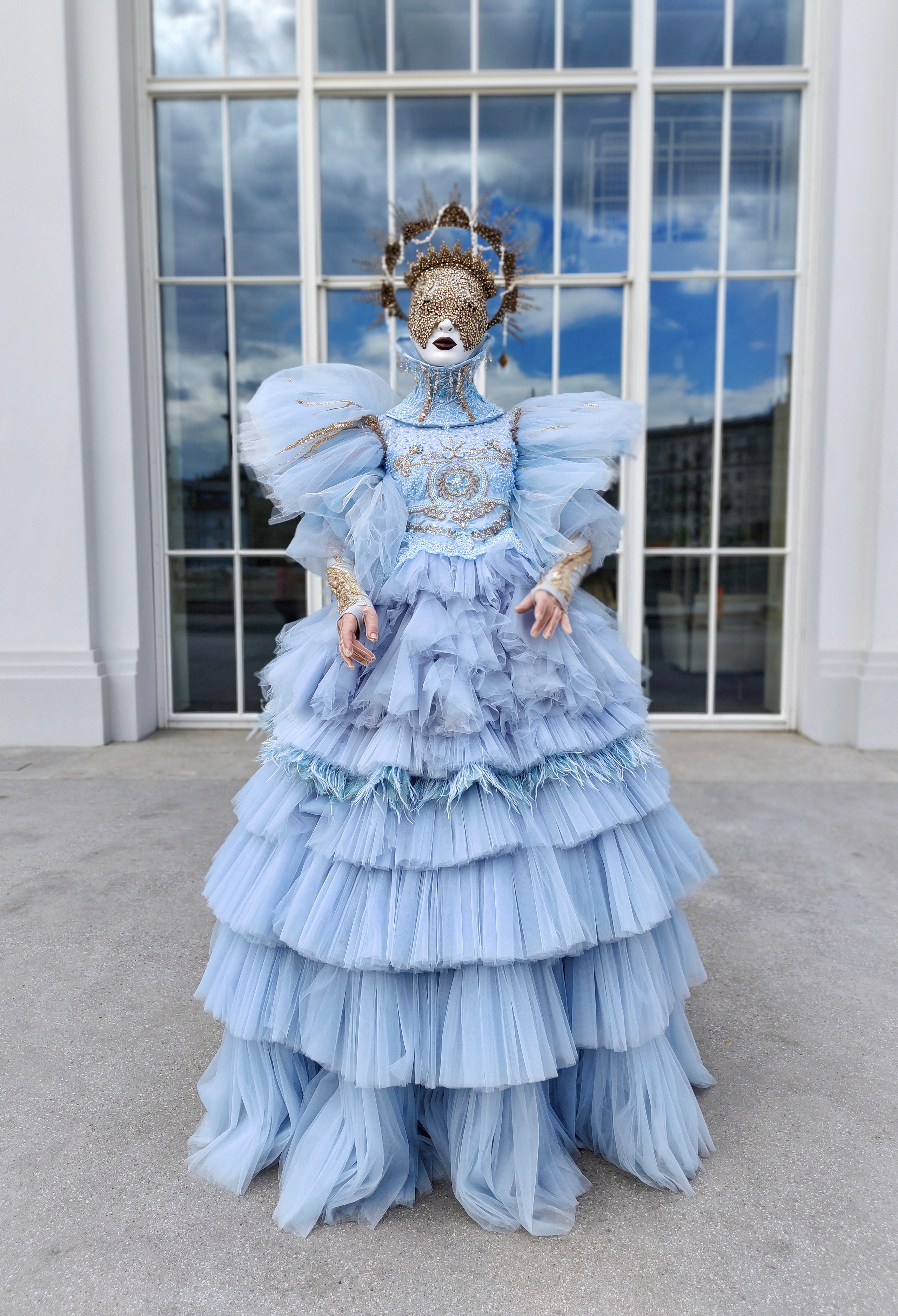 Артист в образе голубого ангела стоит у окна ресторана, встречая гостей.