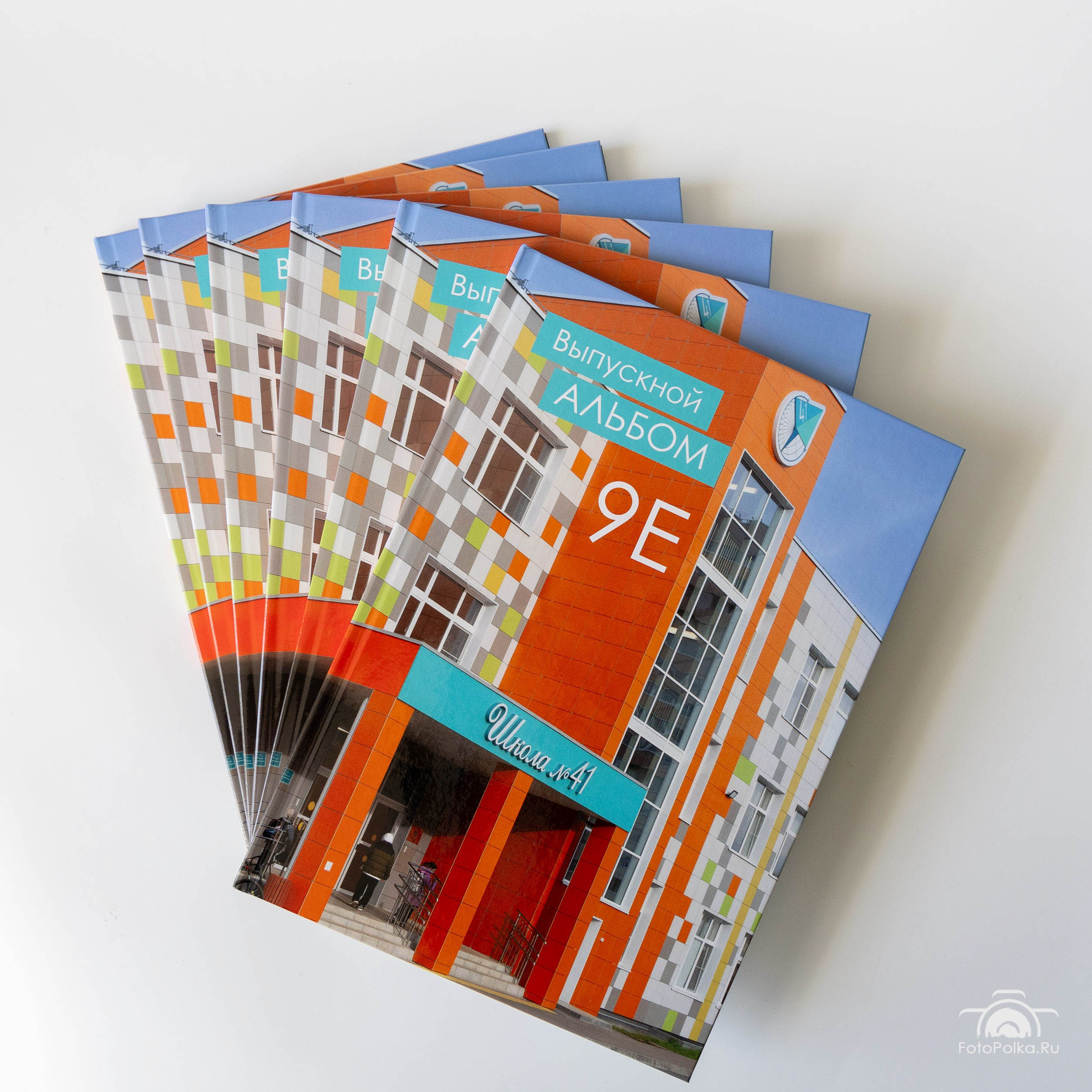 Стопка цветных выпускных фотокниг с белым фоном и бордовым корешком.