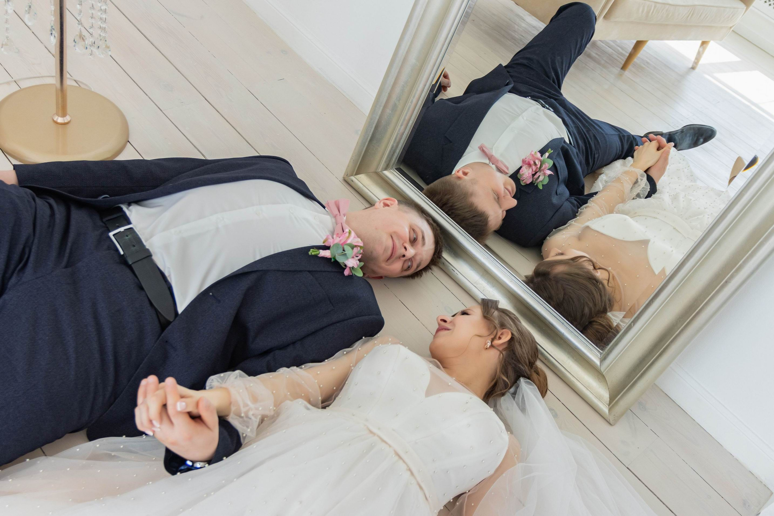 Молодожены лежать у зеркала в фотостудии