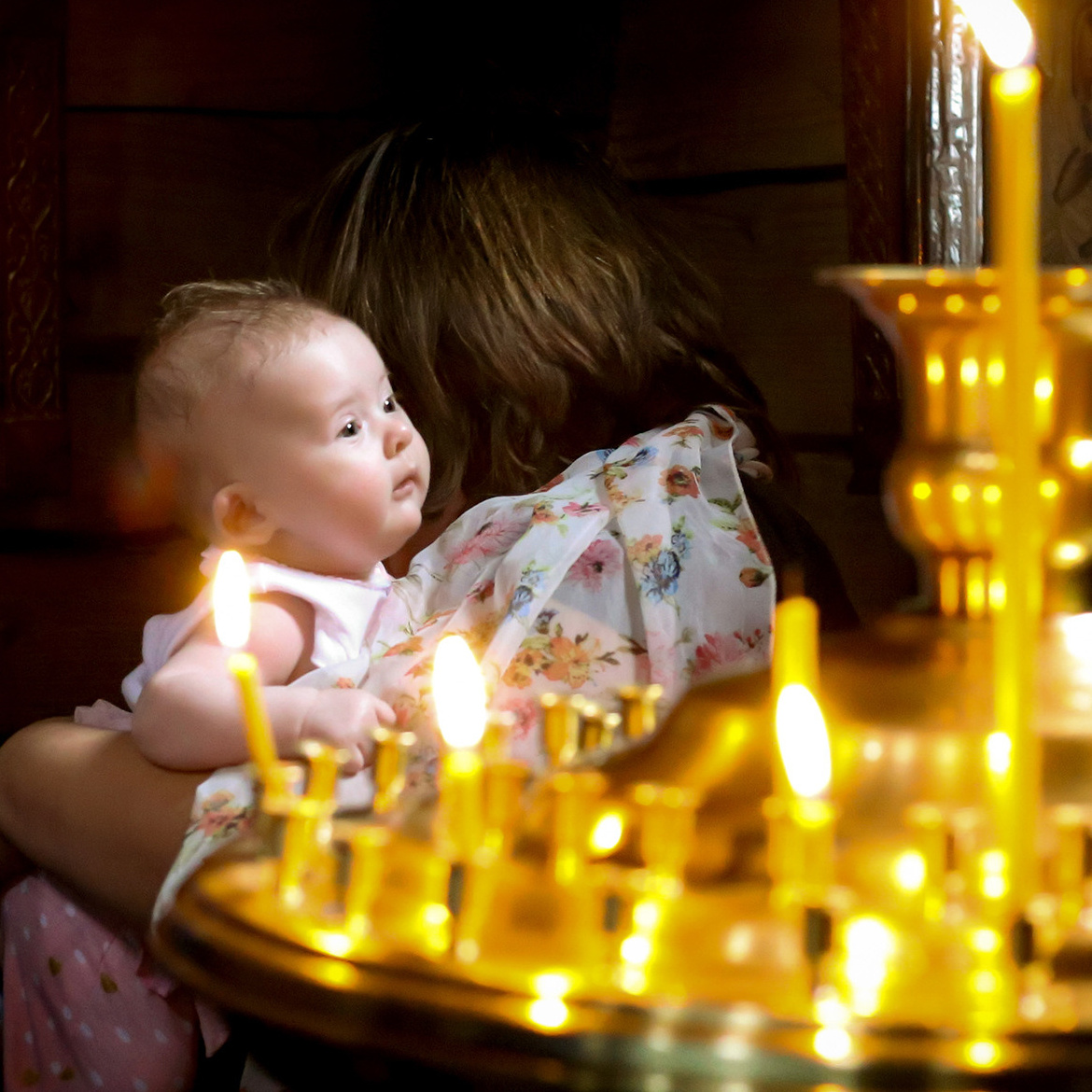 младенец в церкви возле свечей во время обряда крещения