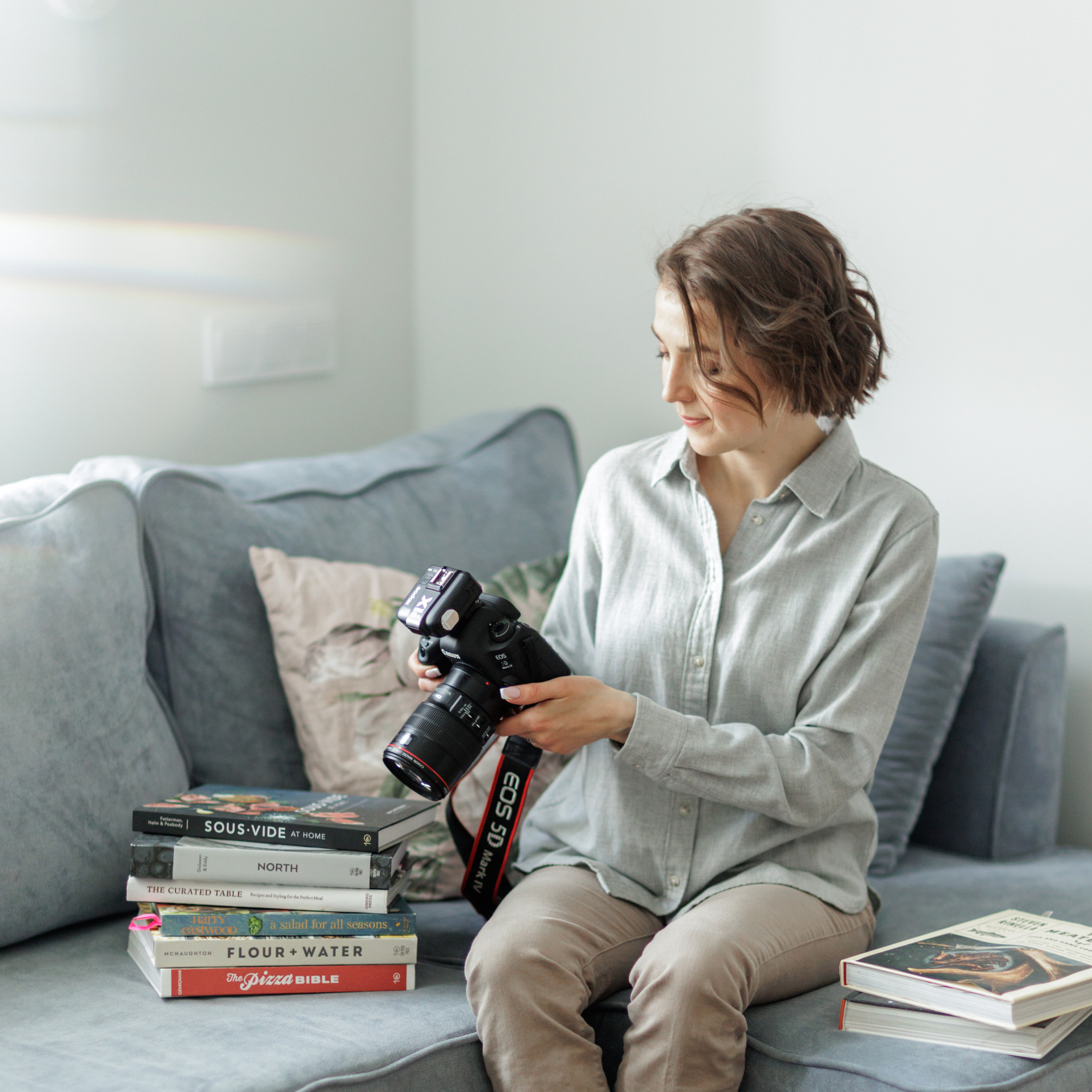 Фуд фотограф в окружении кулинарных книг с фотоаппаратом в руках