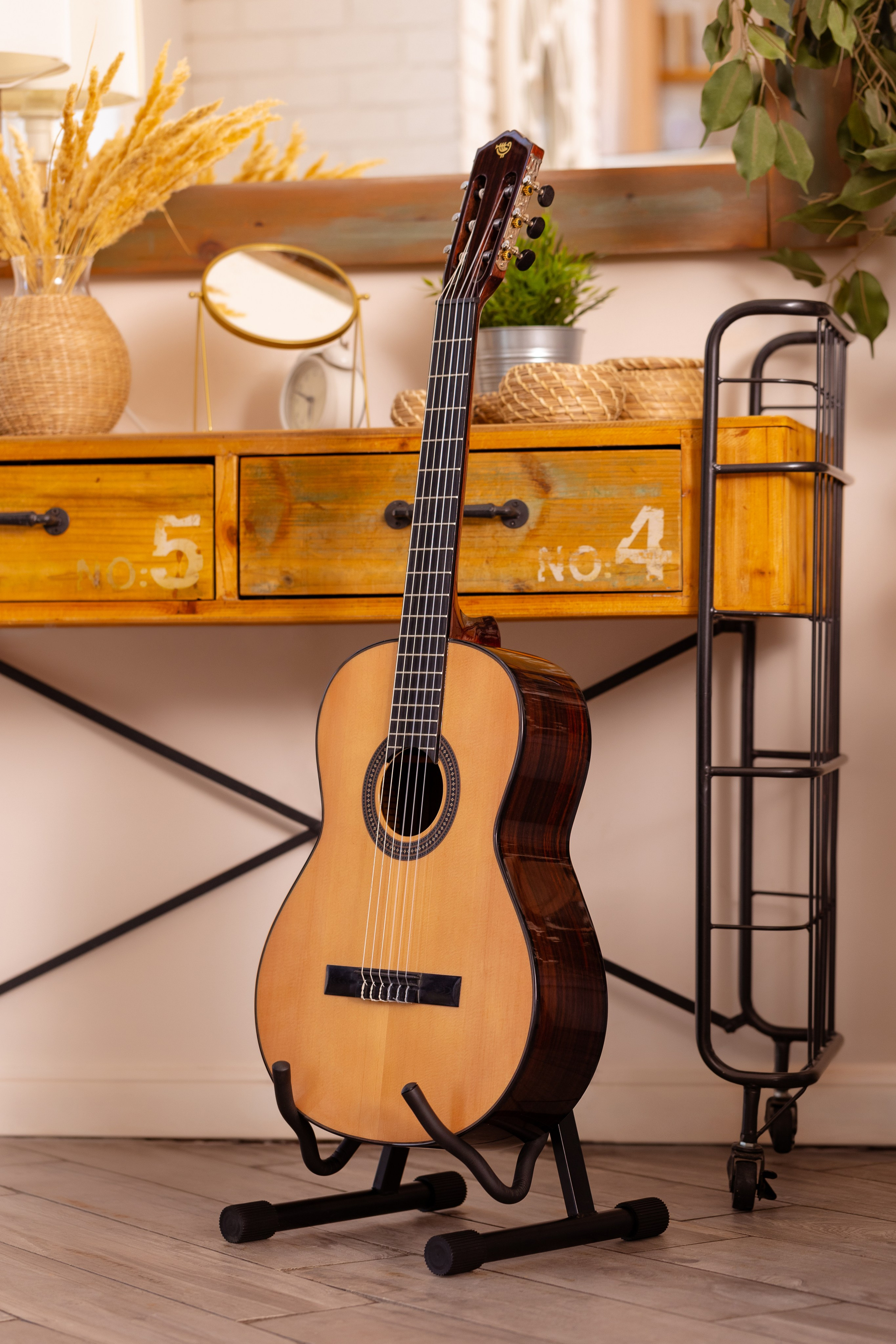 Акустическая гитара стоит на стойке возле туалетного столика в комнате