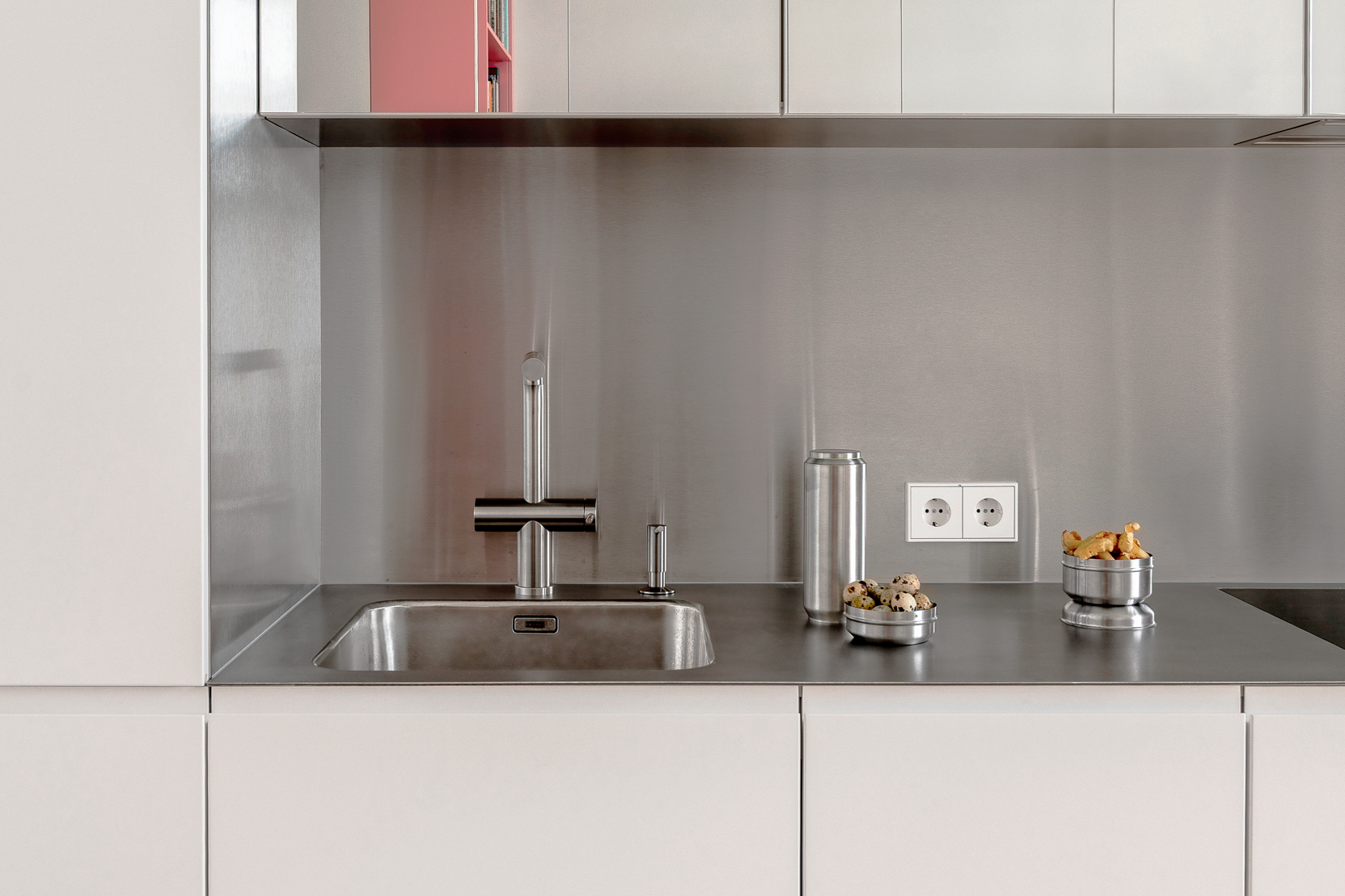 Light kitchen with a stainless-steel backsplash and pink accent