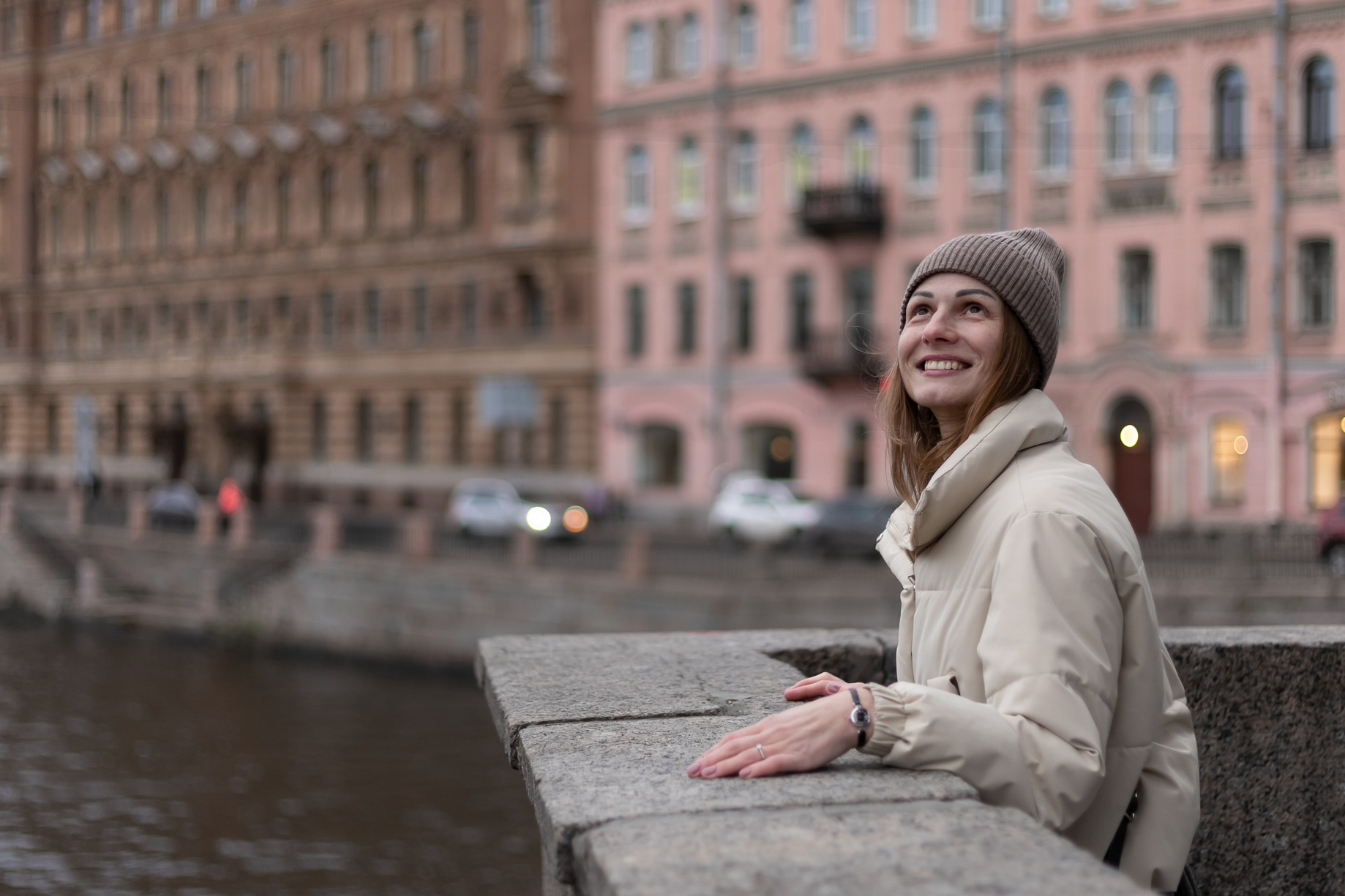 Фото улыбающейся девушки в светлой куртке , стоящей на мосту Ломоносова на Фонтанке 