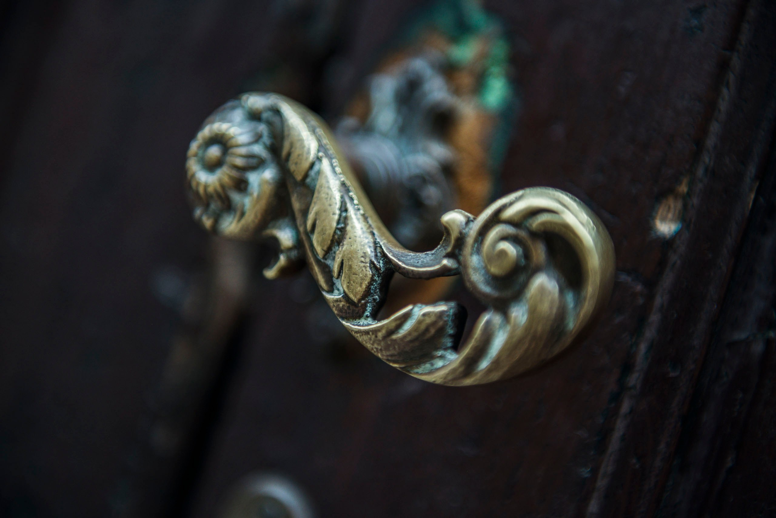 Фотография кованой ручки на деревянной двери в Пьенце. Декор интерьера в тосканском стиле.