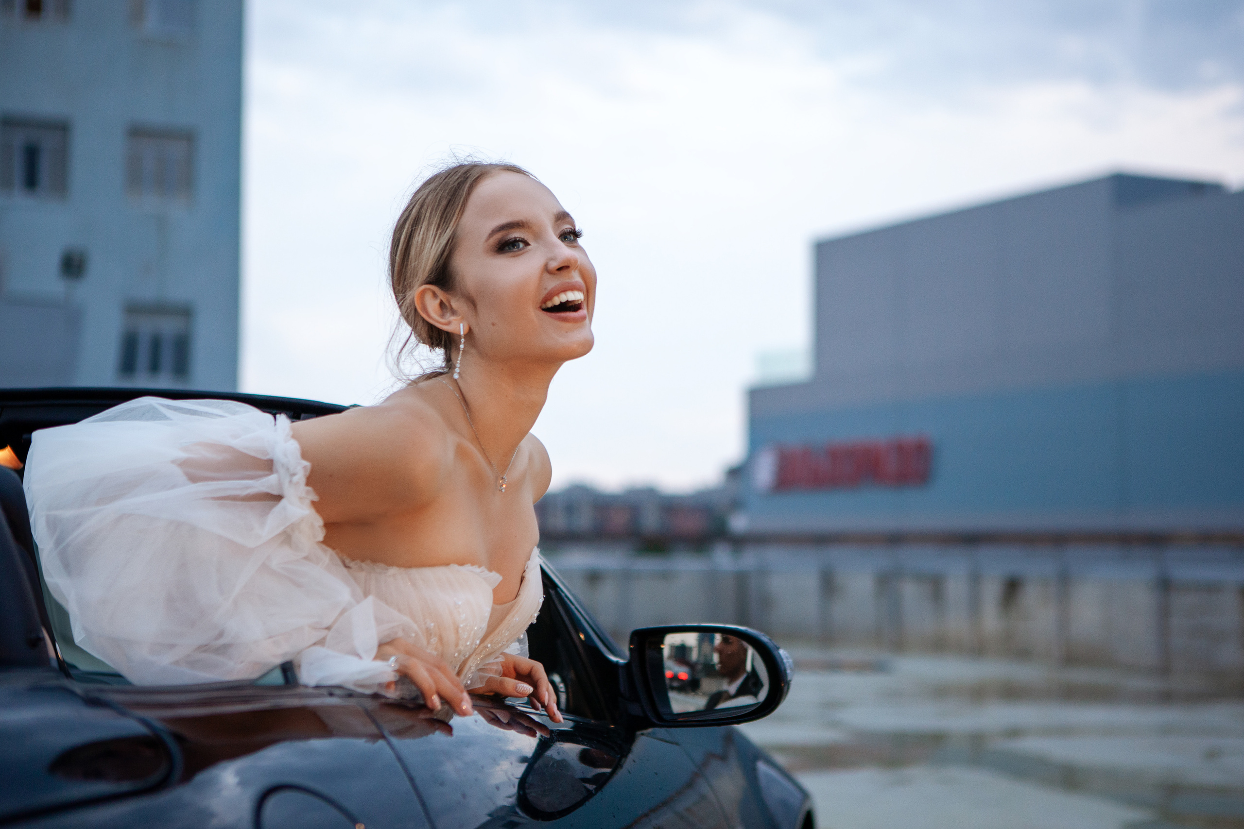 Невеста выглядывает из автомобиля на крыше с видом на город