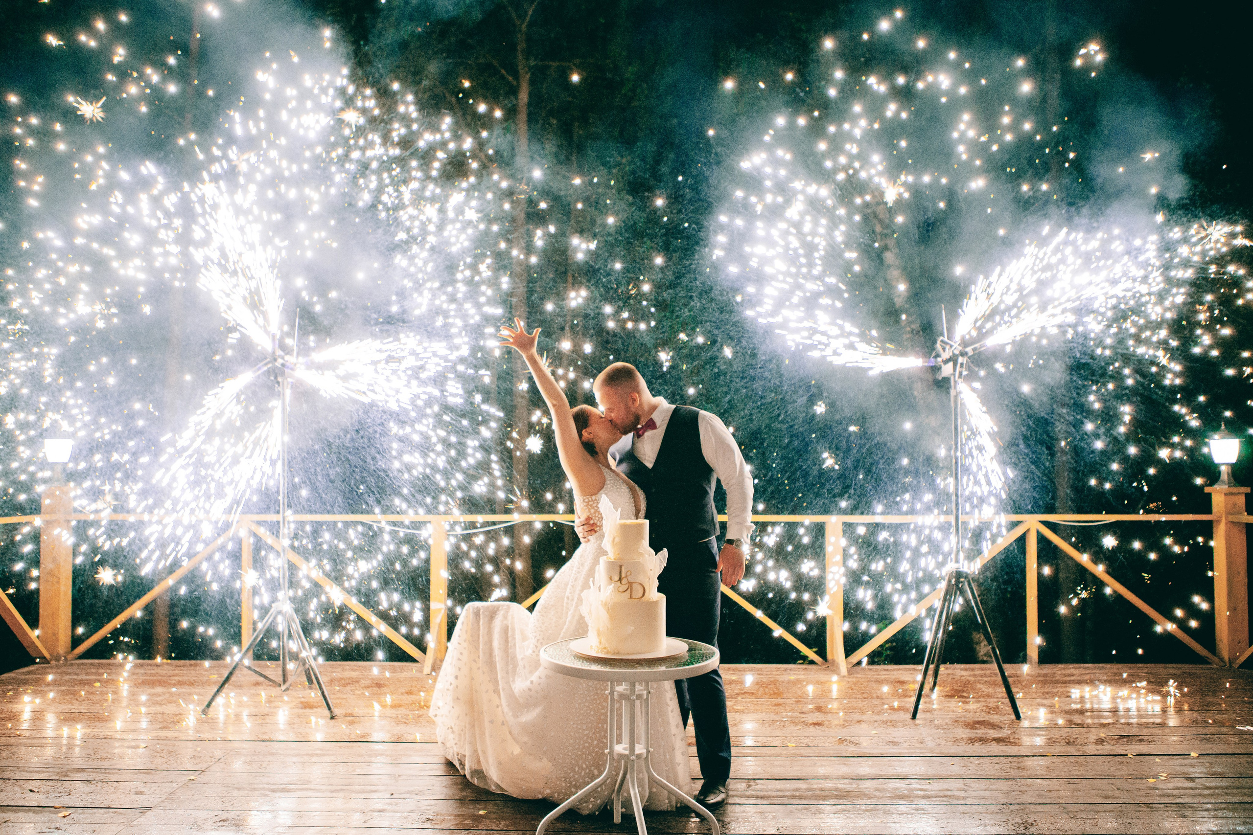 Молодожены целуются на фоне салюта, фейерверка и бенгальских огней