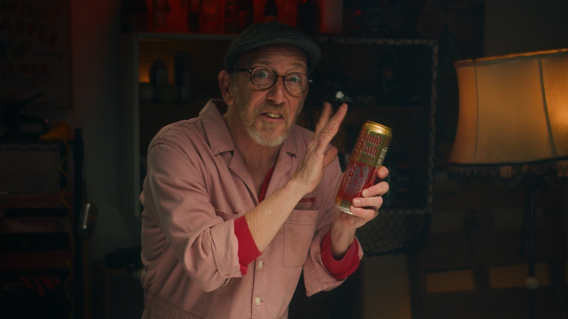 Elderly man indoors, holding a product can and explaining its features, captured in warm lighting.