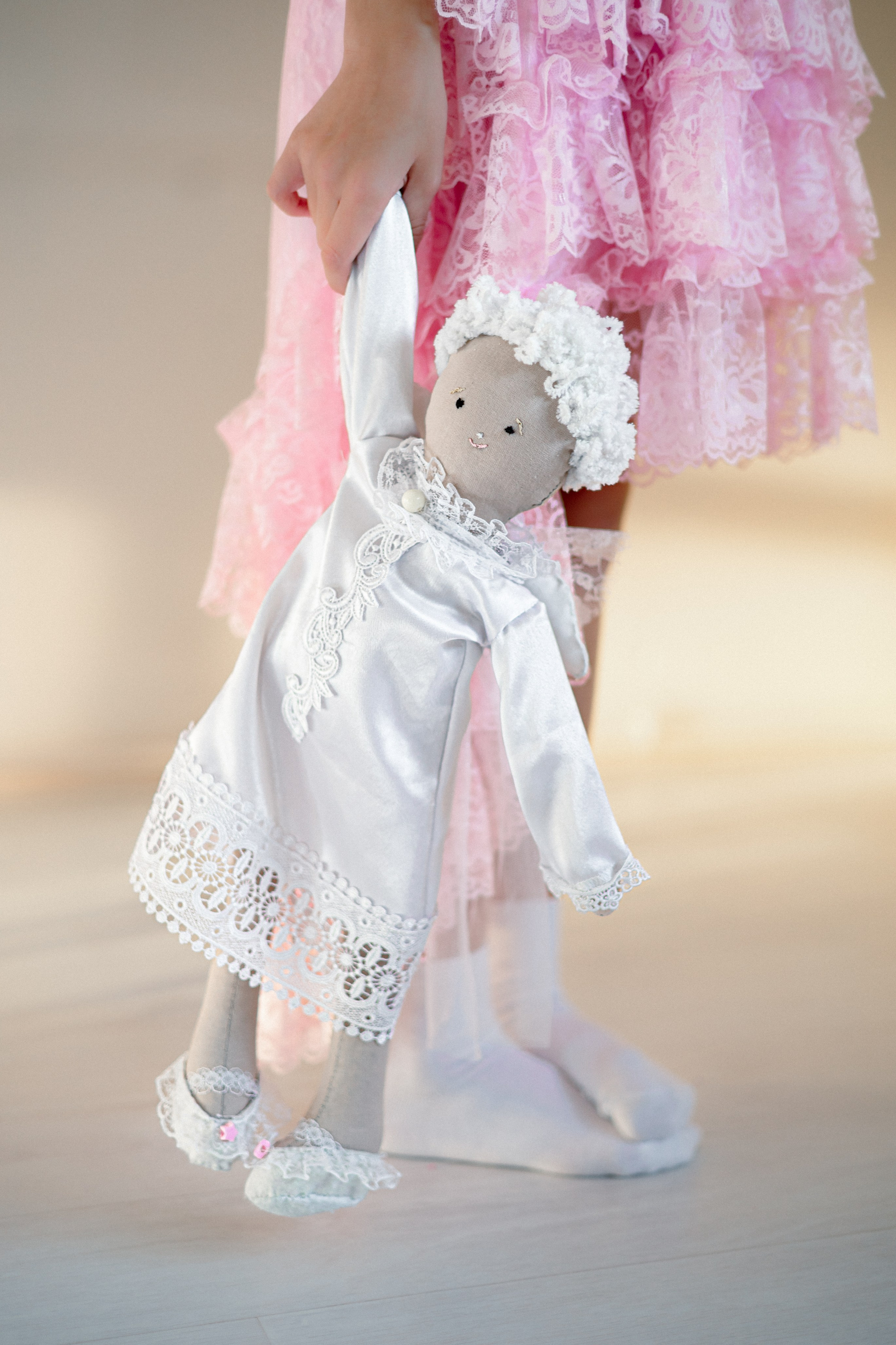 Девочка держит в руках интерьерную игрушку ангела, которую она сшила своими руками на курсе шитья и дизайна